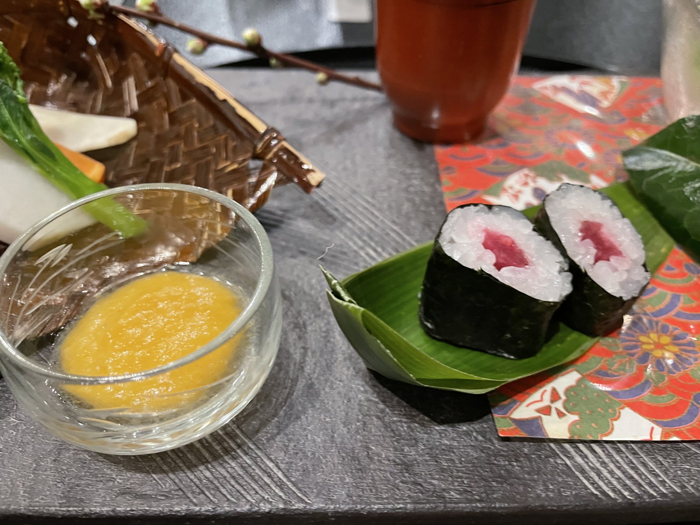 Rolled sushi on a leaf, with the dip in the foreground.