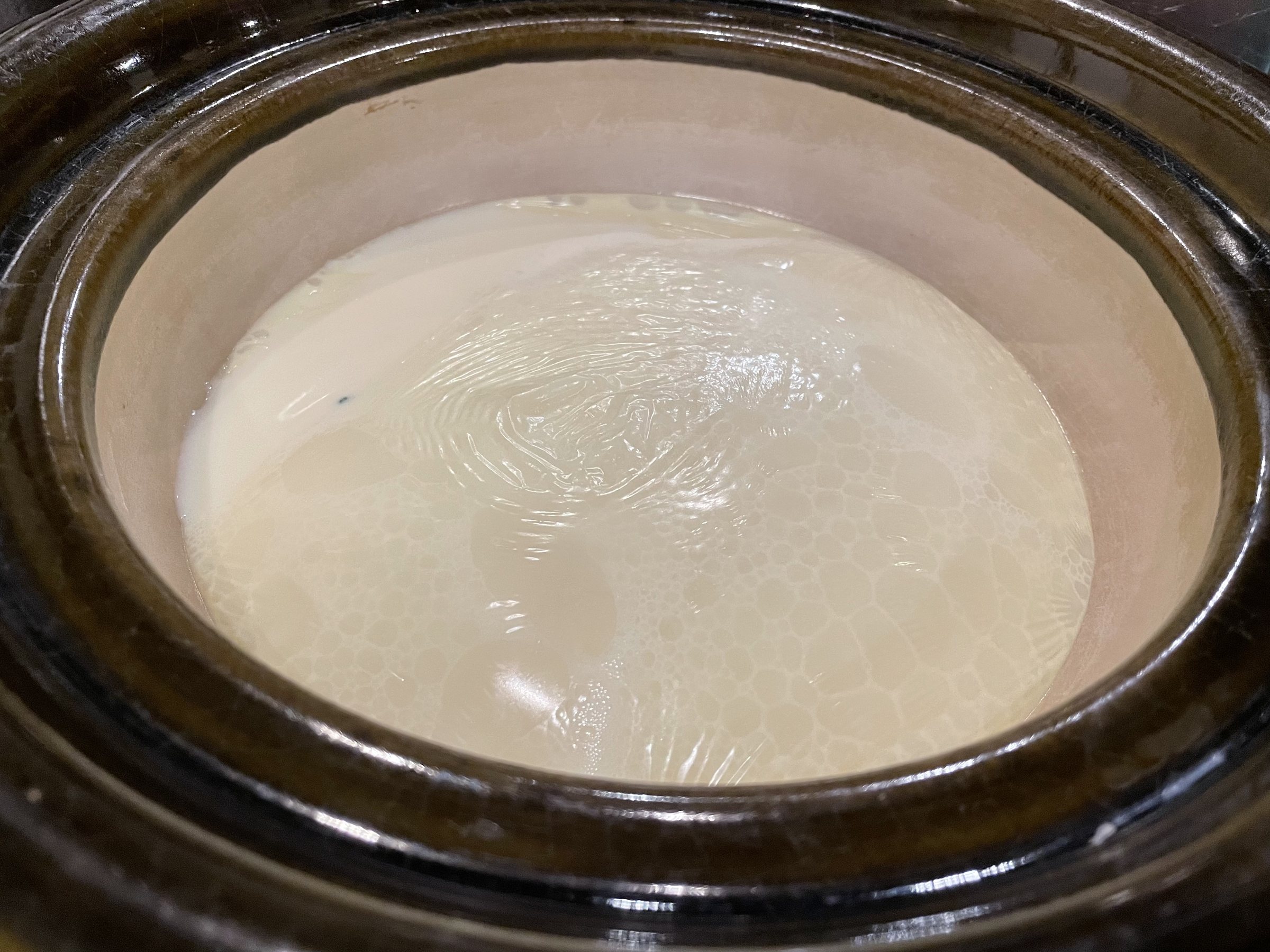 The soy-milk broth warming in an earthenware pot.