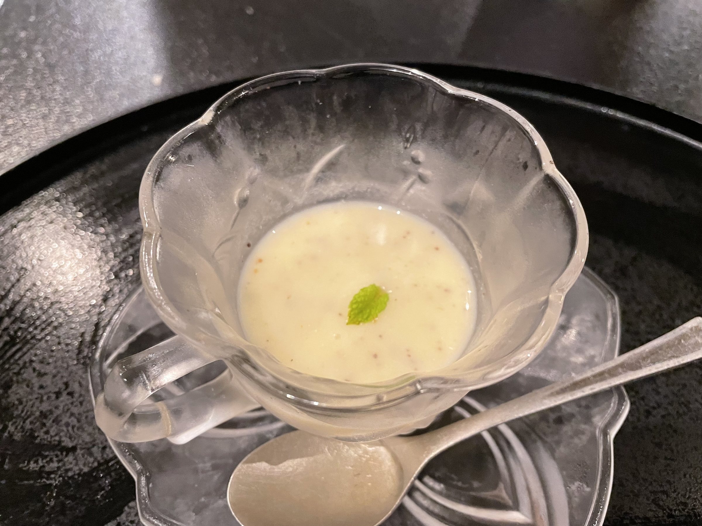 A creamy soup in a glass cup with a single green leaf.