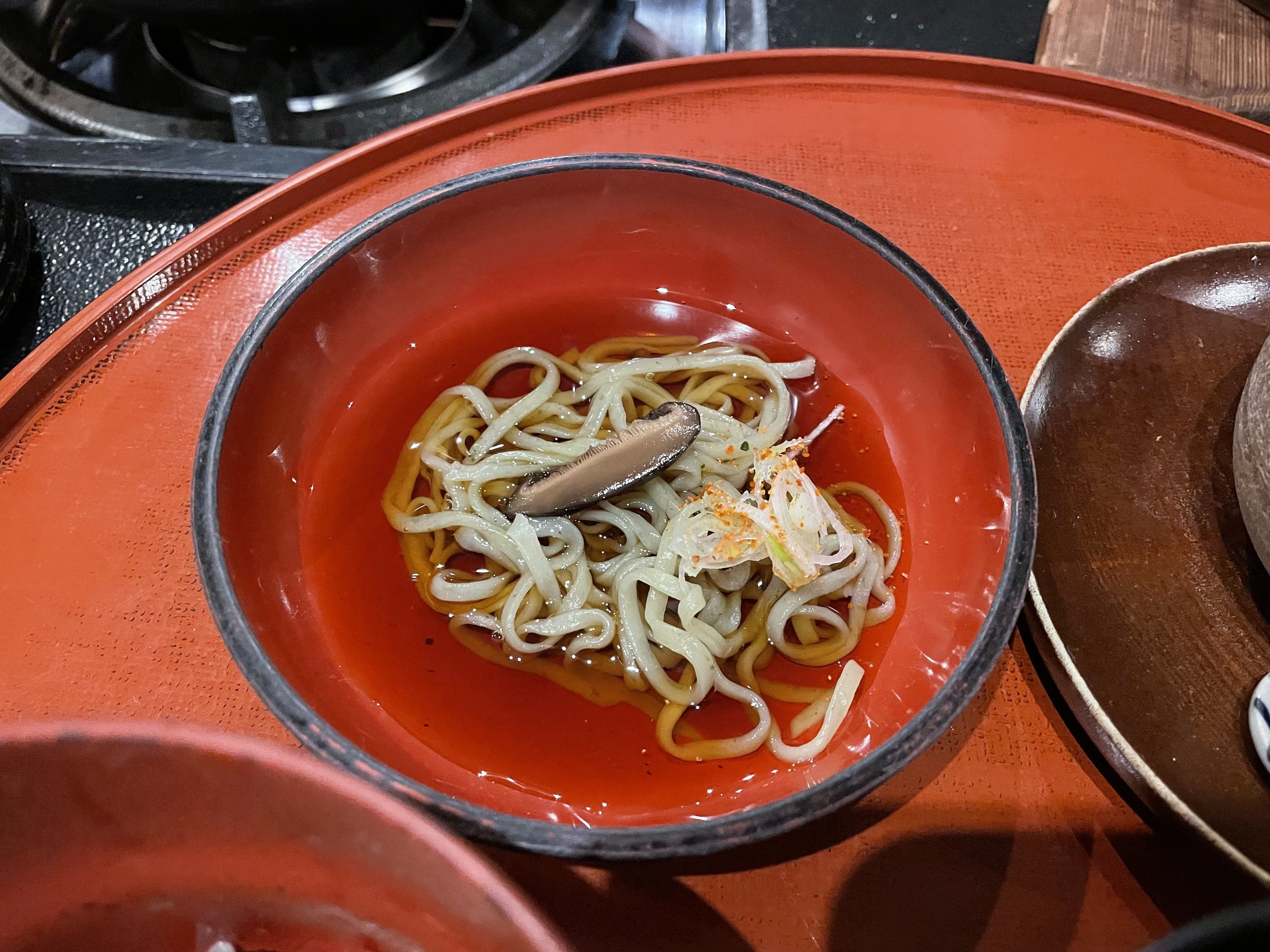 Handmade udon with shiitake in a red lacquer bowl.
