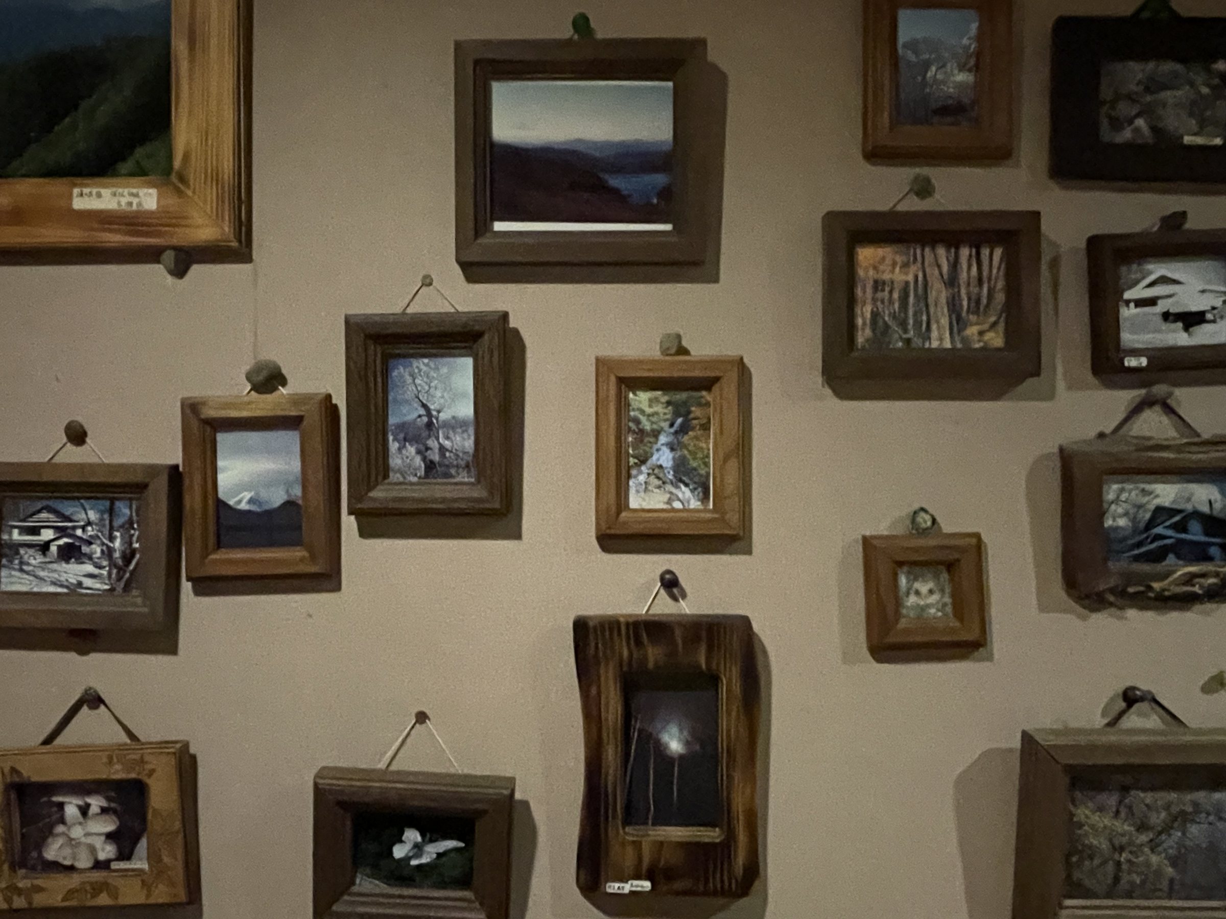 A wall hung with small photographs in rustic wooden frames.