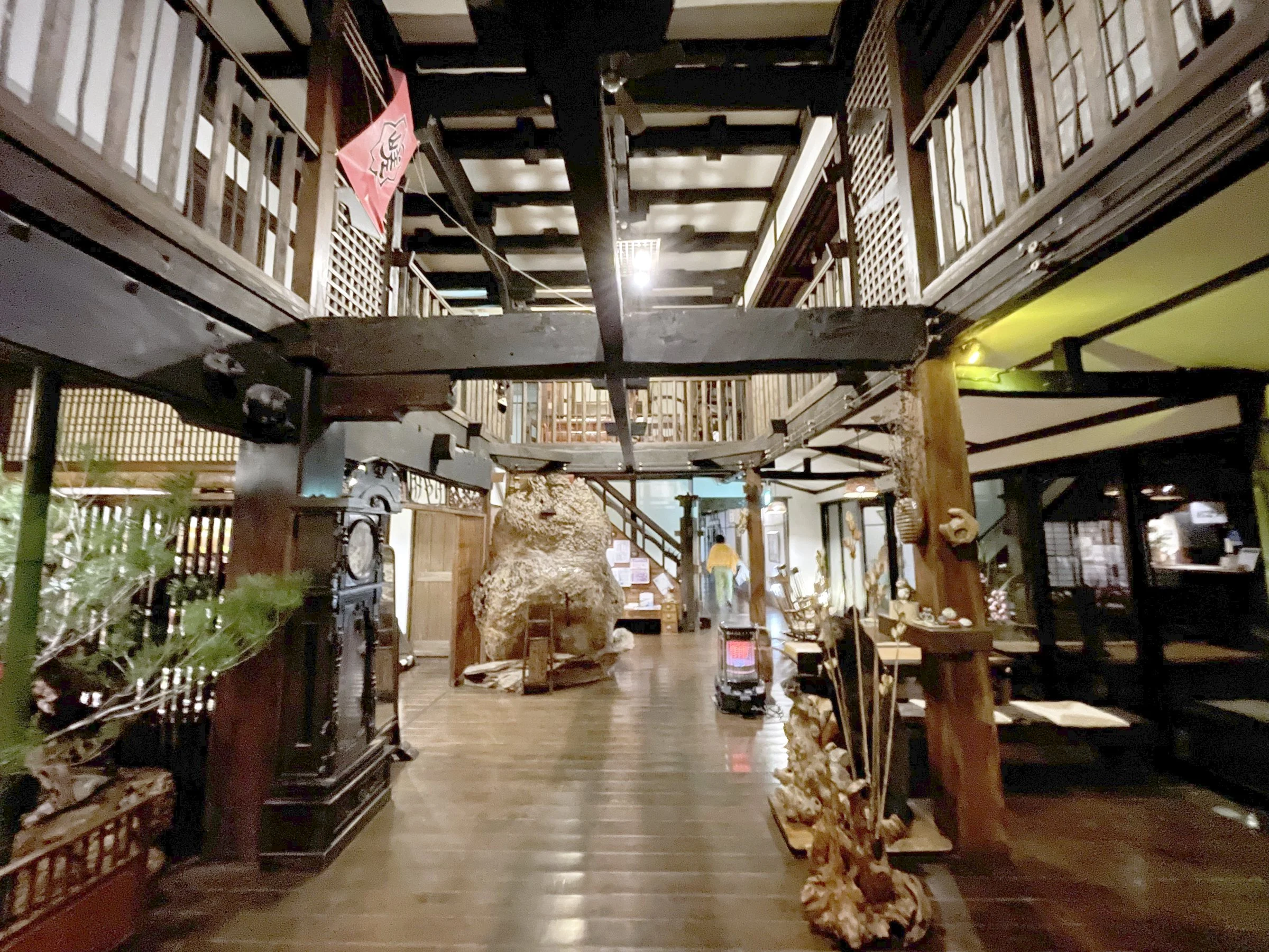 The timber-framed hall at night, with dark polished floorboards, a large carved wooden figure and galleries above.