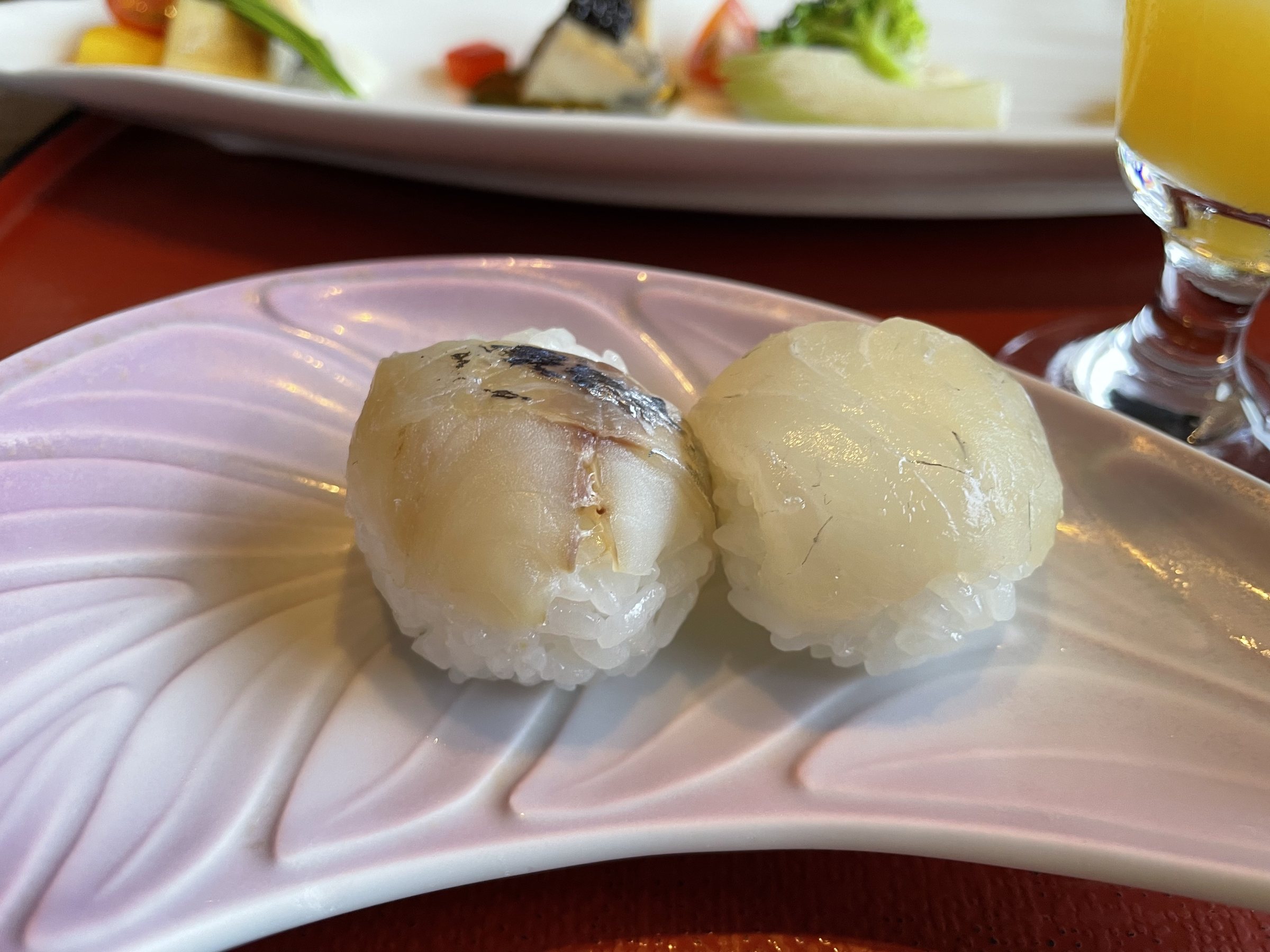 Two small temari sushi on a pale pink dish.