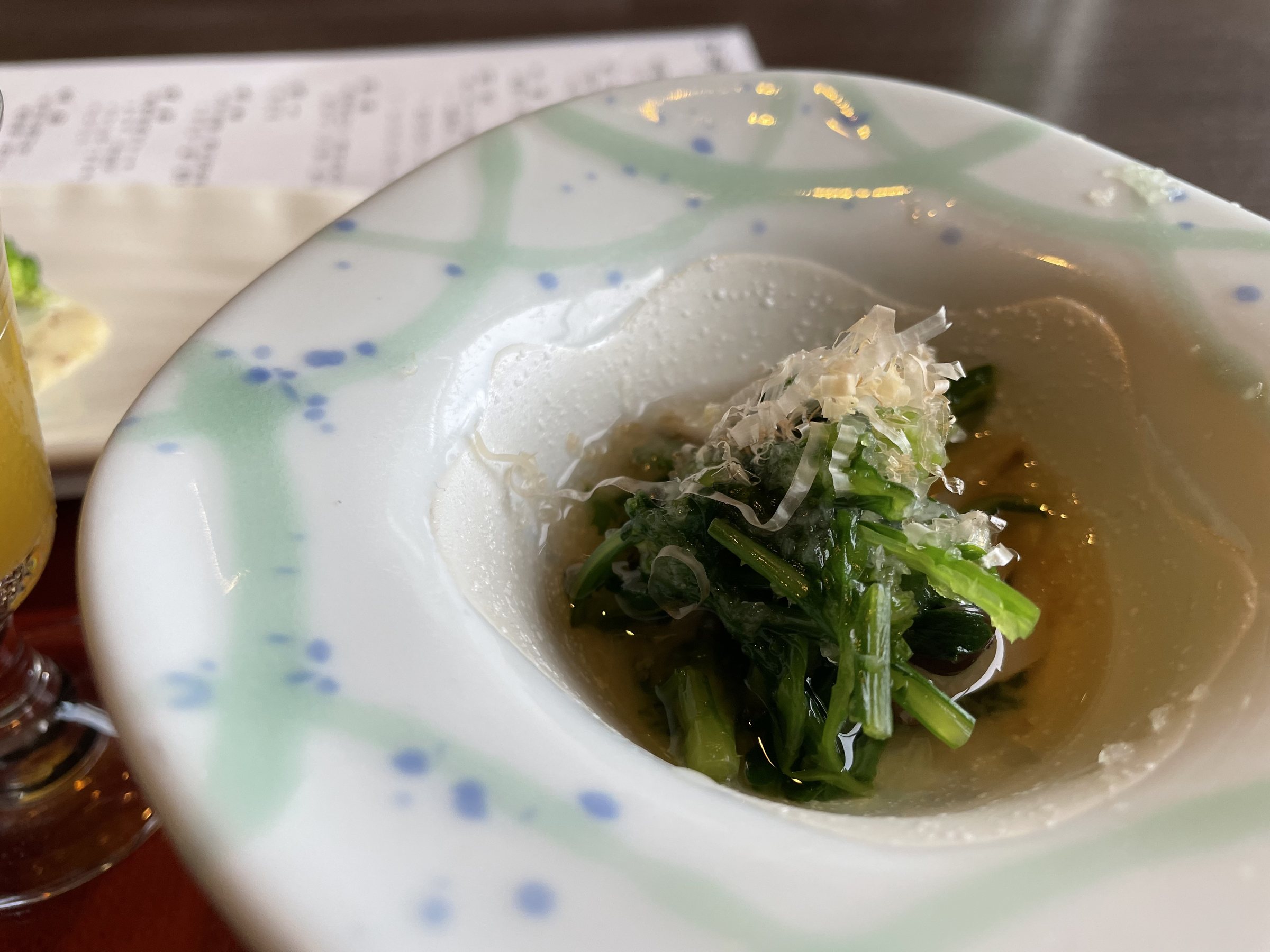 A small bowl of greens in broth, scattered with fine shreds.