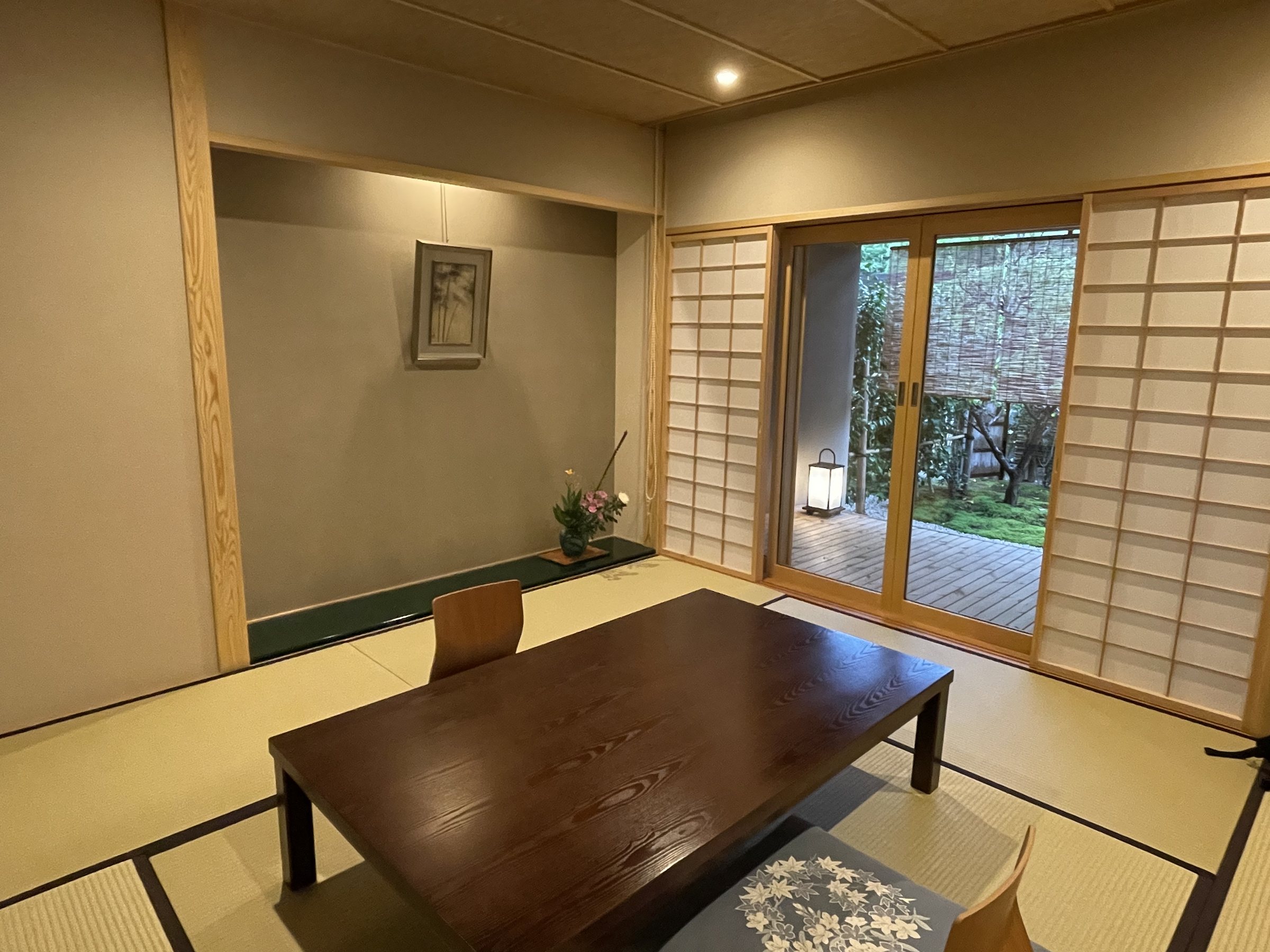The tatami room, with a low table and floor cushion, and the garden beyond the shoji.