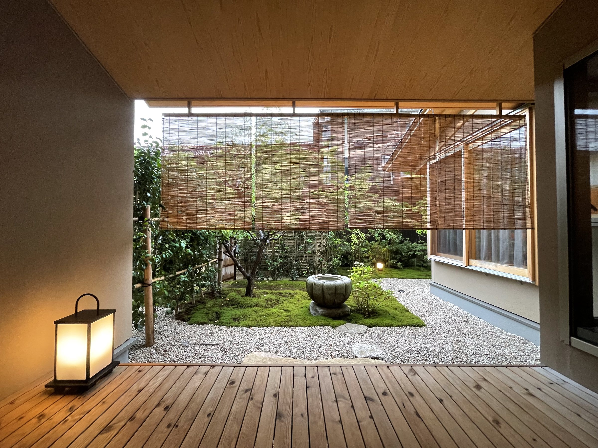The room’s wooden veranda and its small garden of moss, gravel and a stone basin, screened by bamboo blinds.