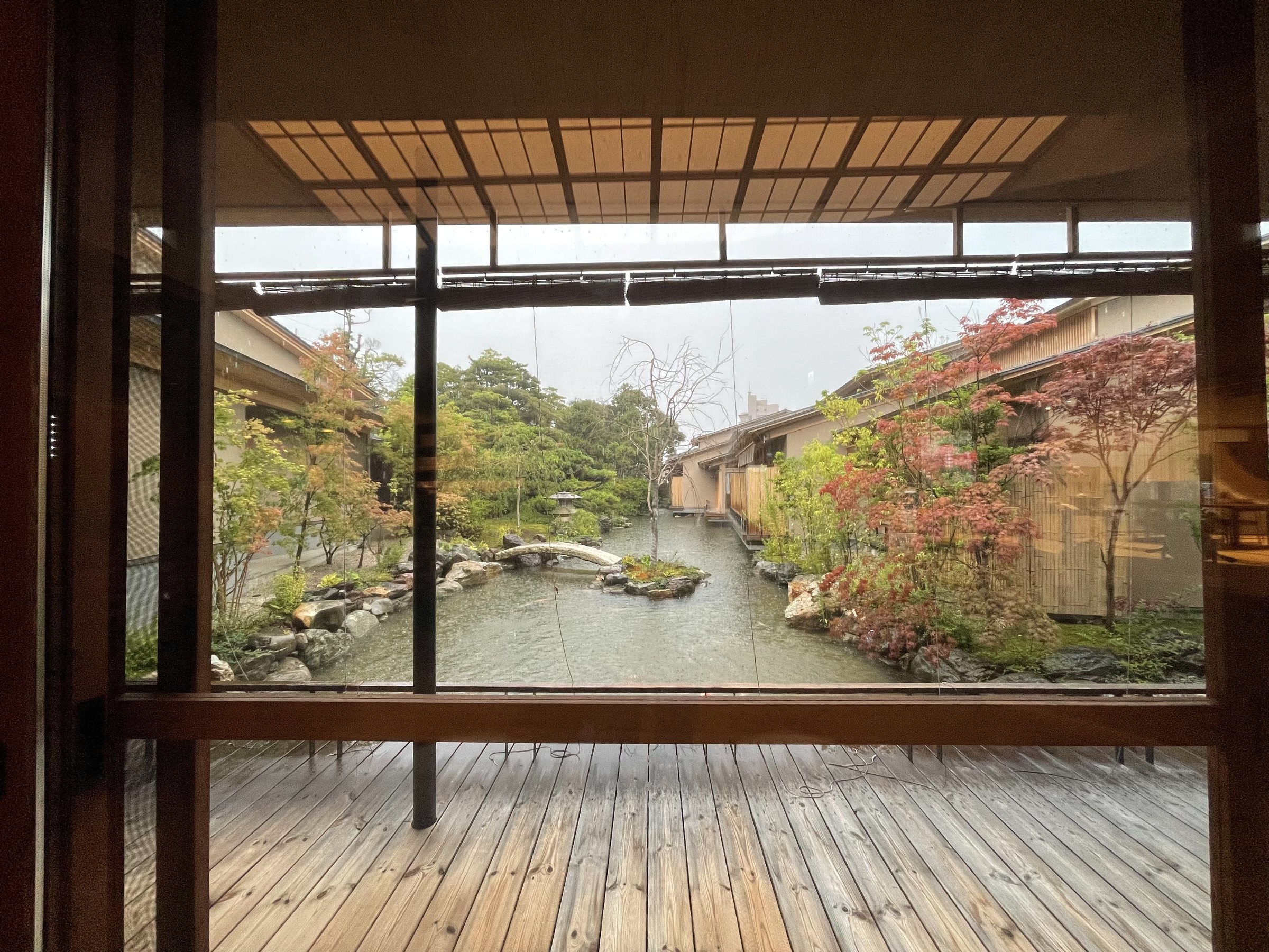 From the lounge, a wooden deck looks out over the garden pond in the rain.