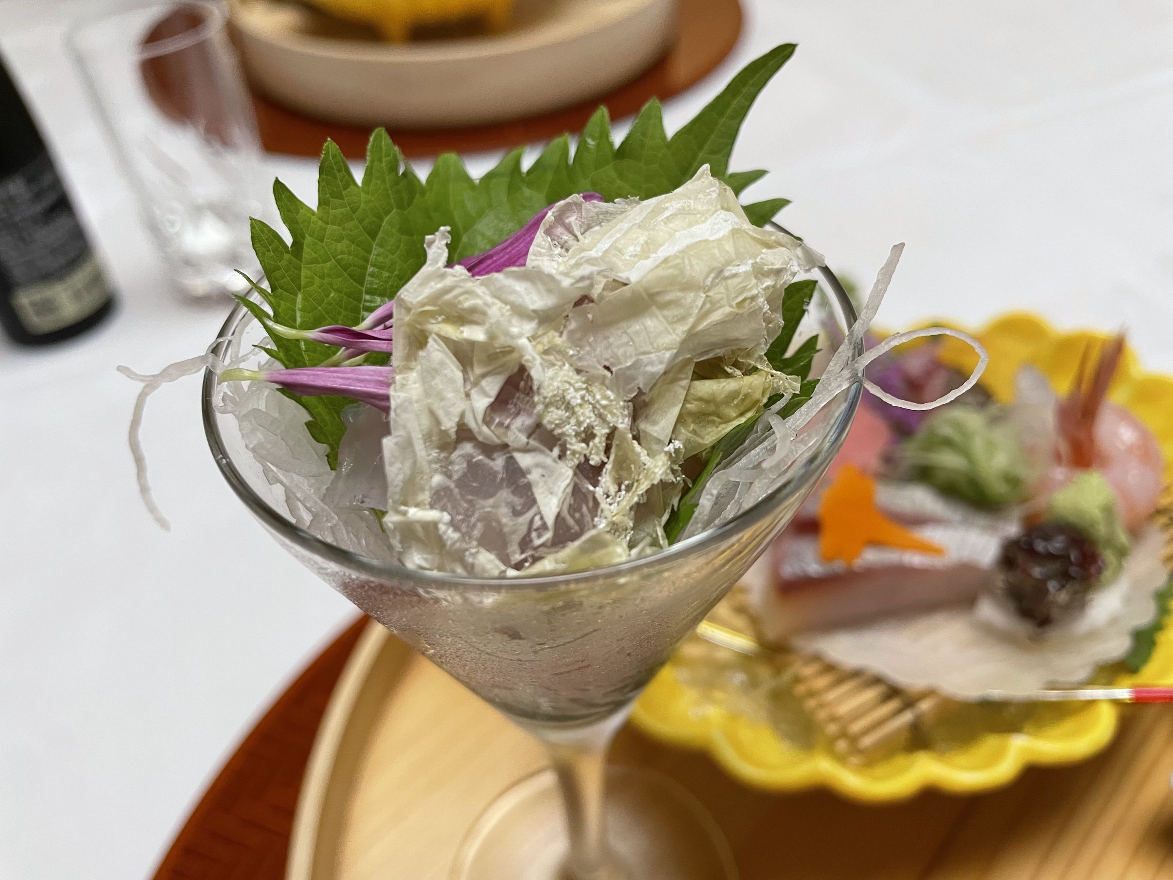 The glass of sashimi under a veil of oboro kombu.