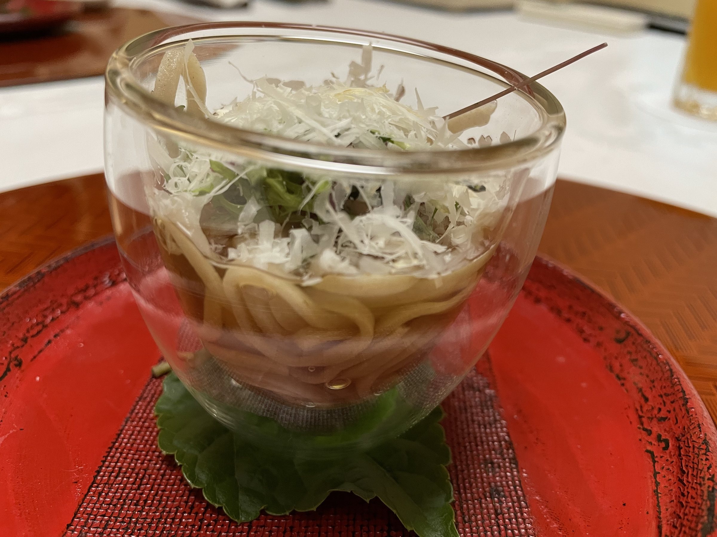 Echizen soba topped with grated cheese, in a glass bowl.