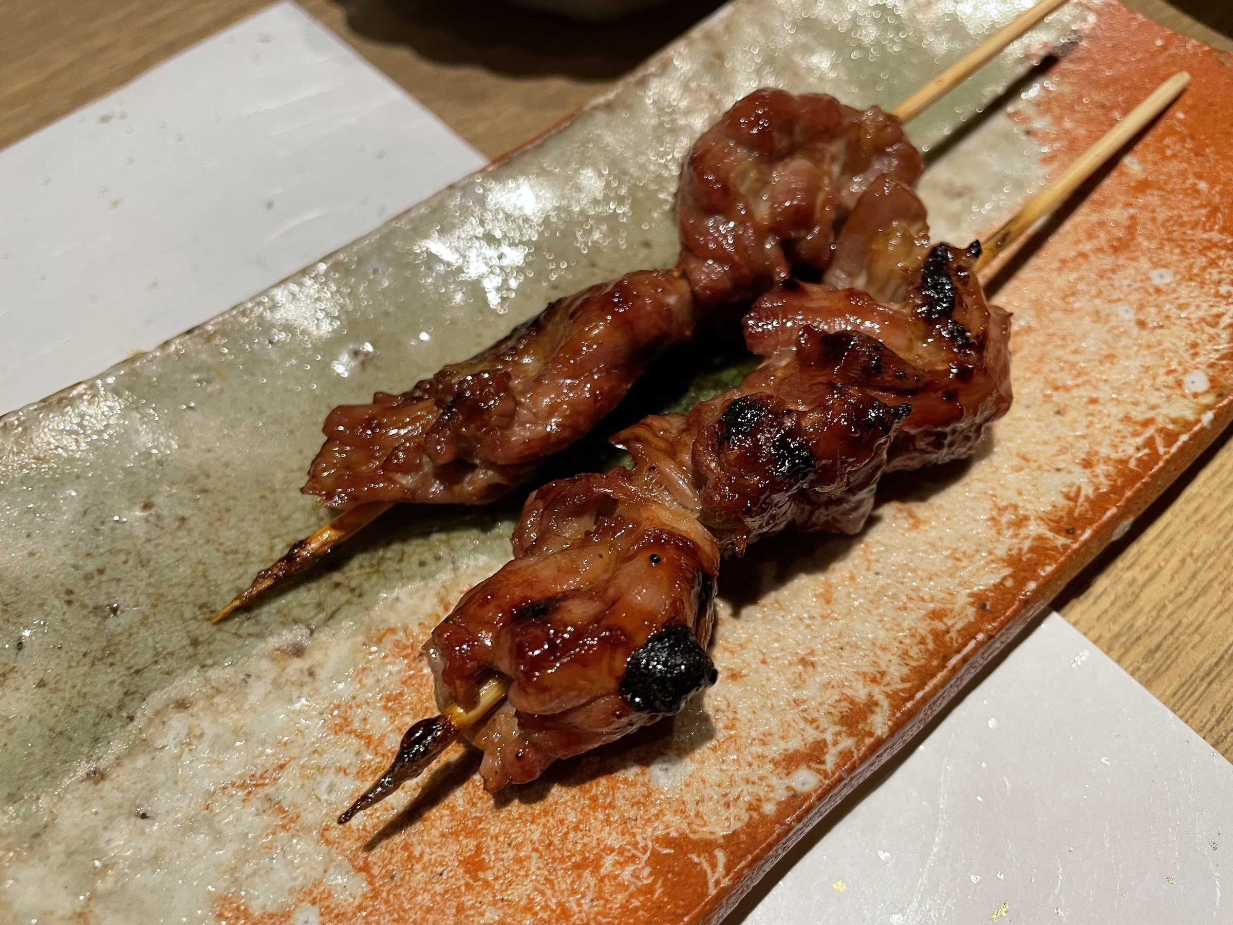 Two glazed, grilled skewers on a long plate.