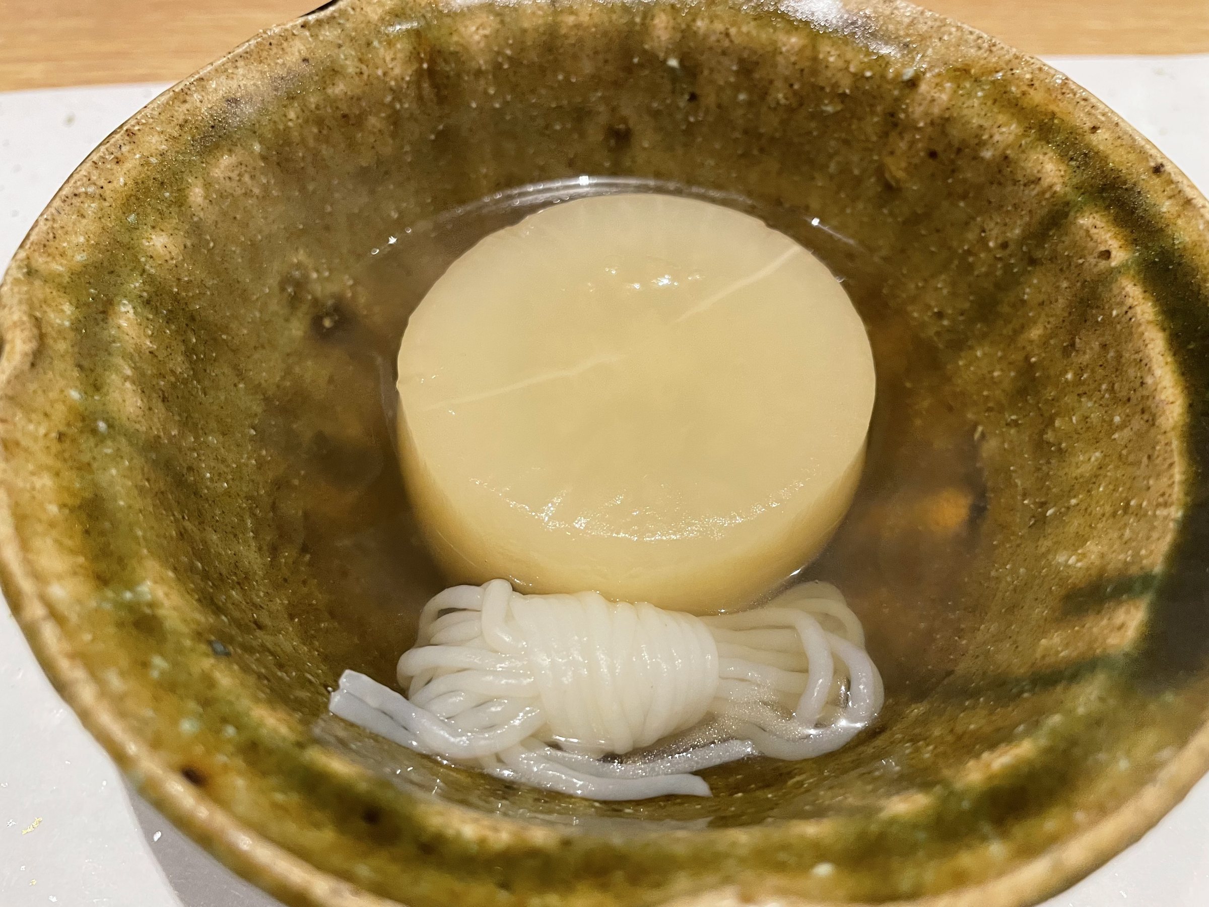 A round of simmered daikon over a coil of fine white noodles in clear broth.