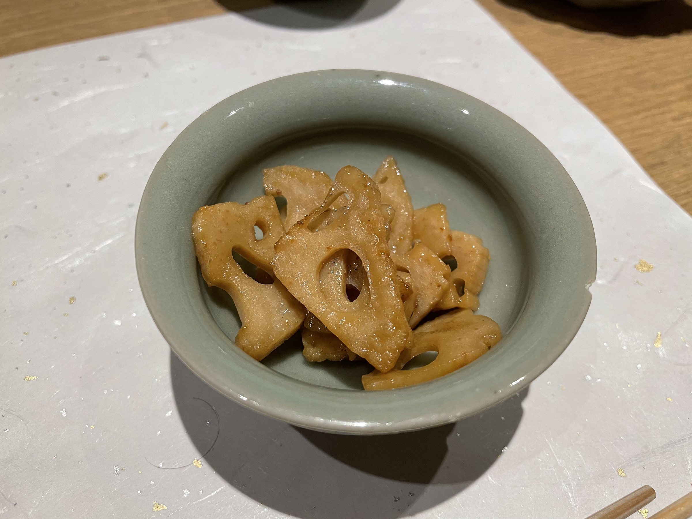 Glazed slices of lotus root in a celadon bowl.