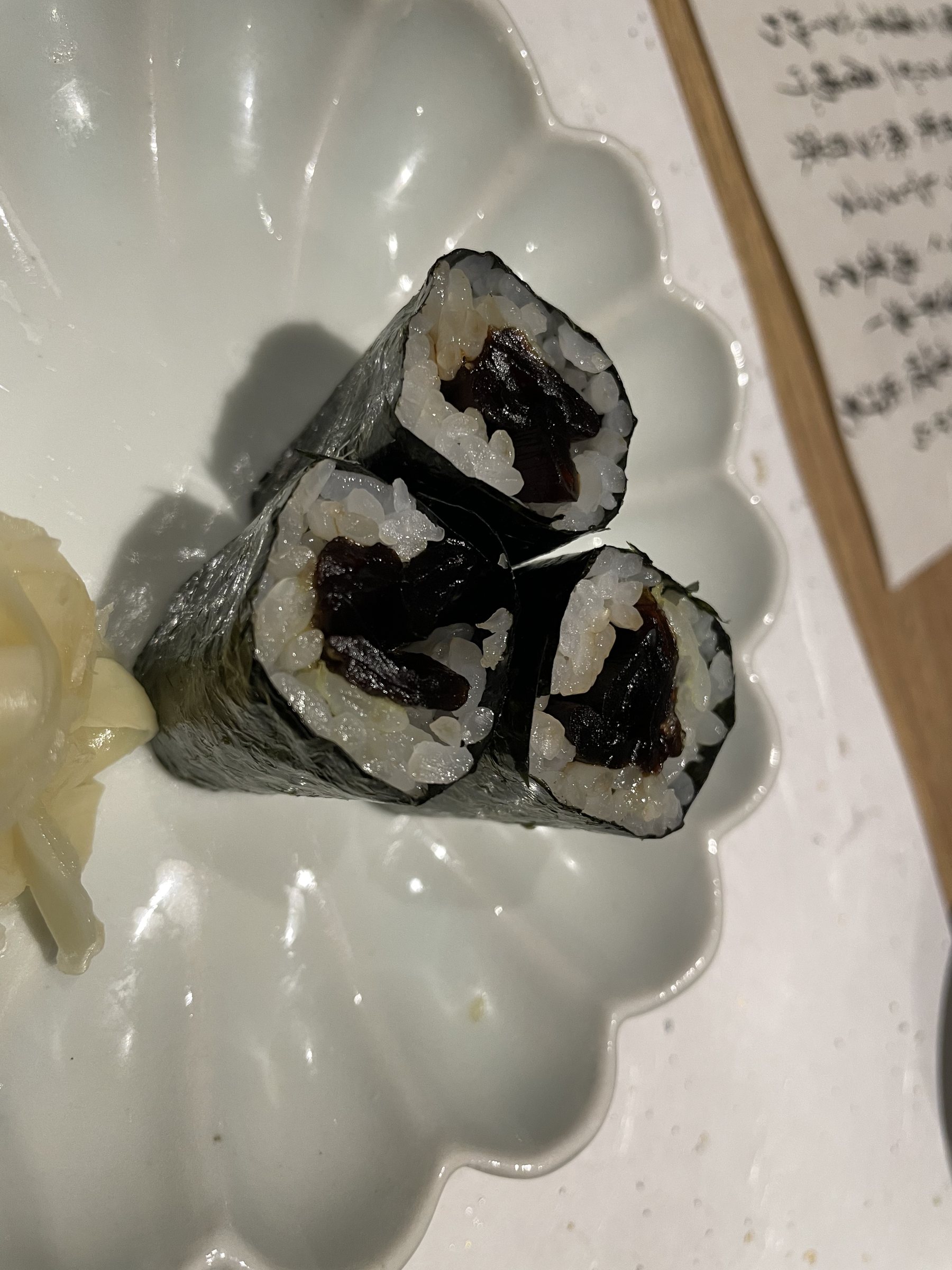 Thin nori rolls with a dark, glossy filling, and pickled ginger.