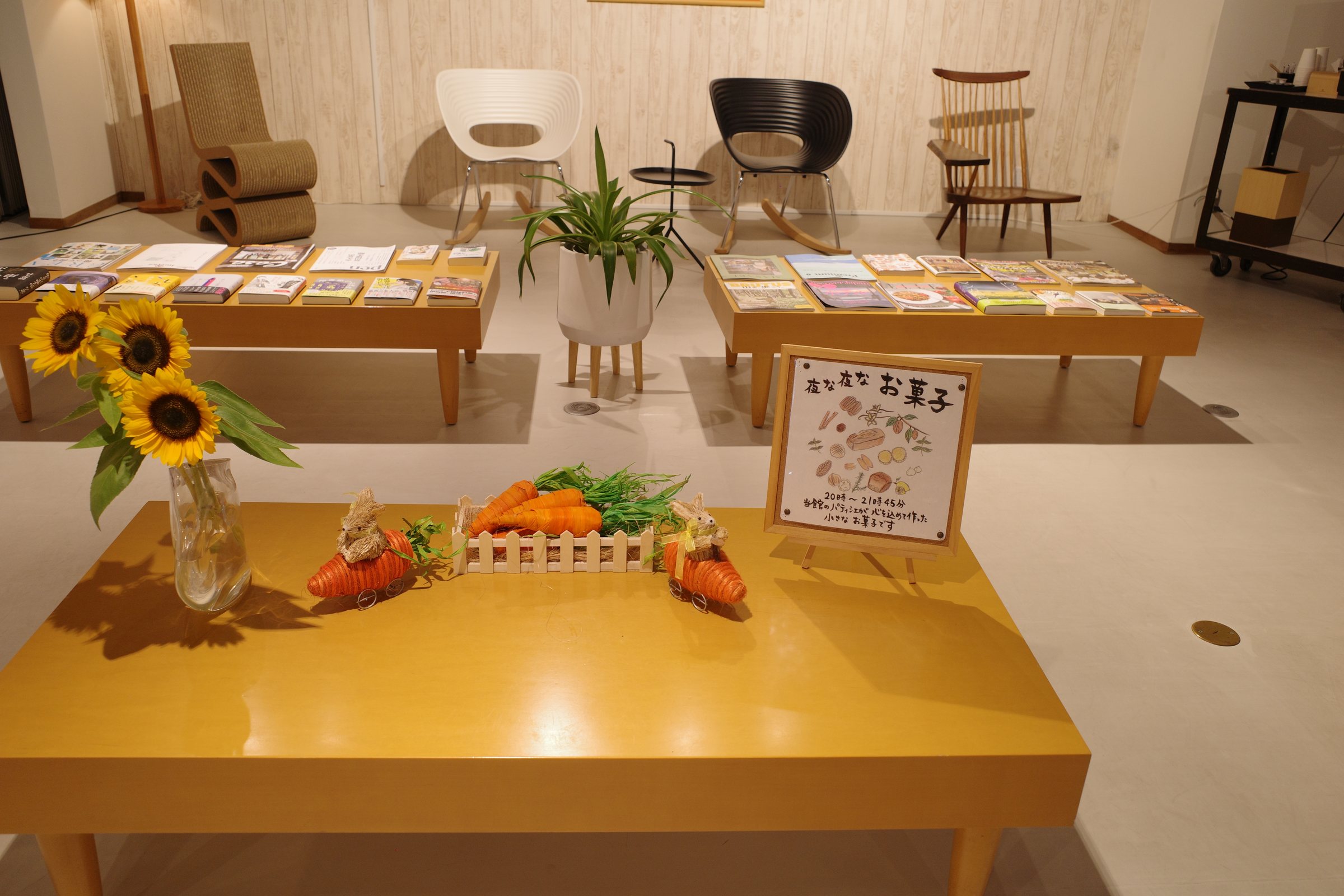 A table of sunflowers and fresh vegetables in the library corner.