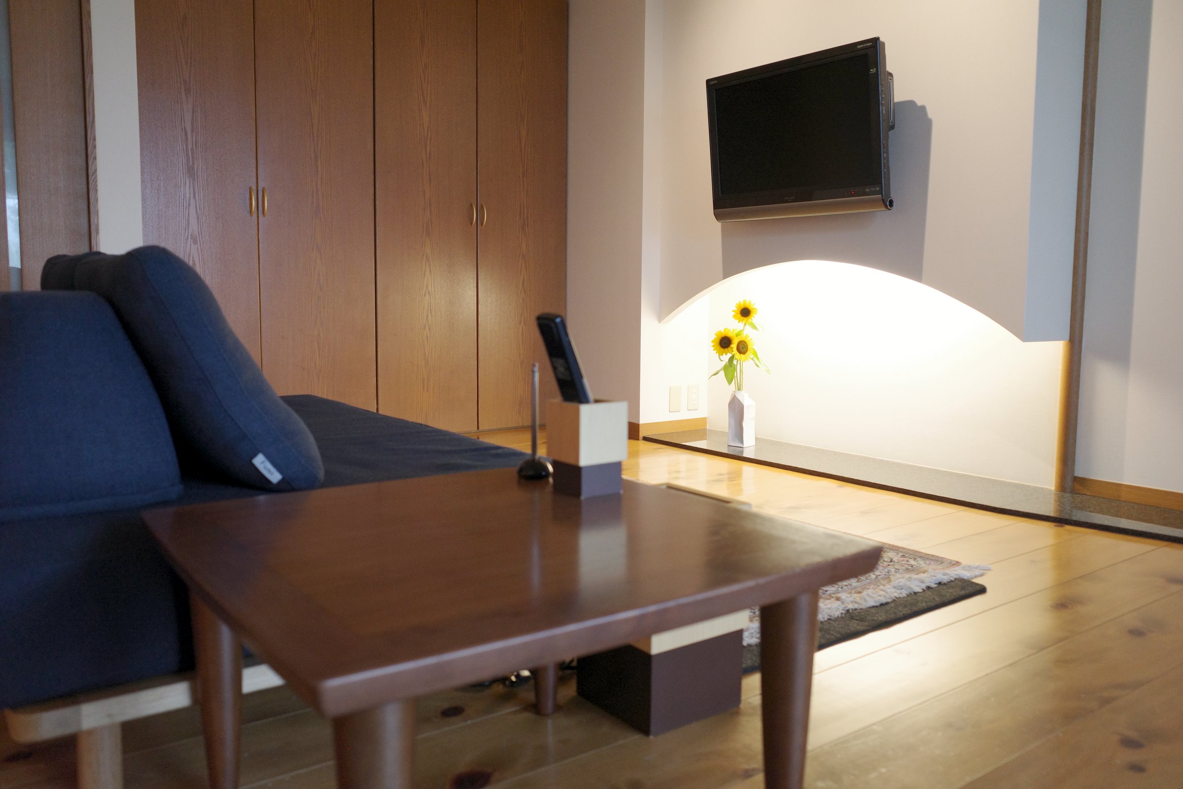 The neighboring living room, with a sofa and a wall-mounted television.