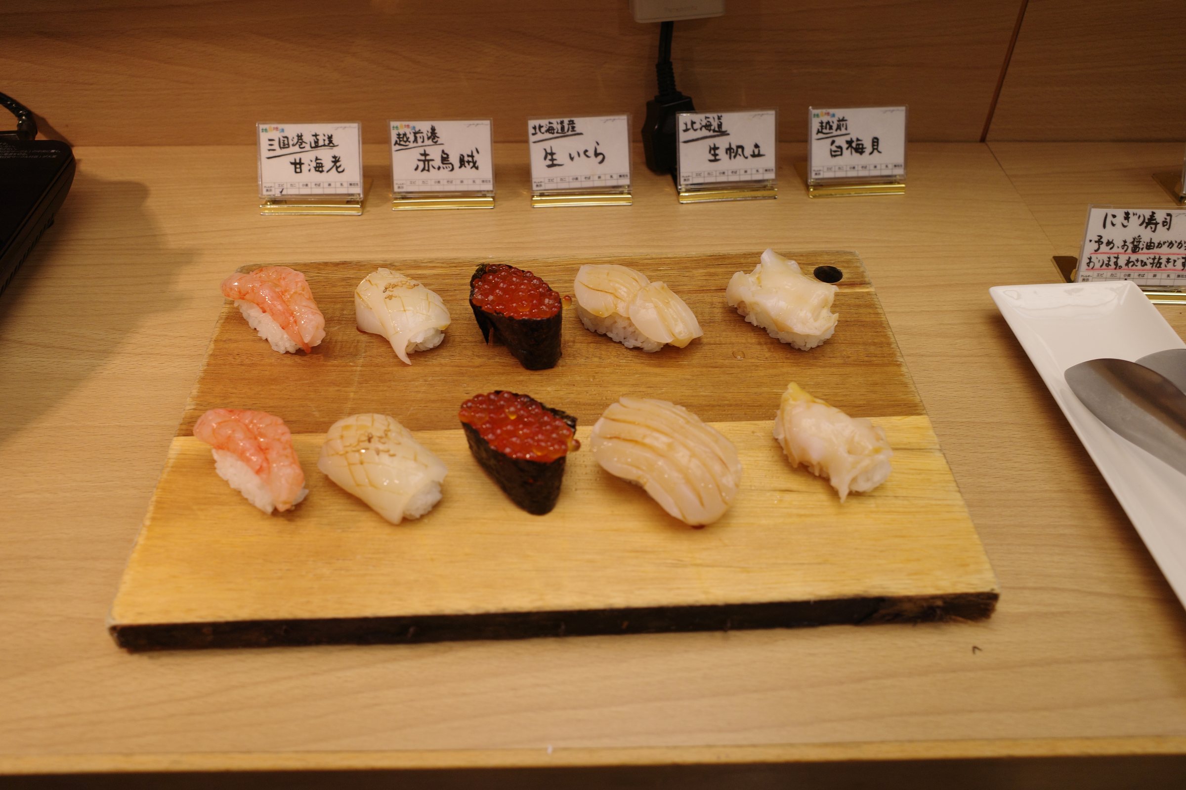 More nigiri, including salmon roe and white fish, with labels.