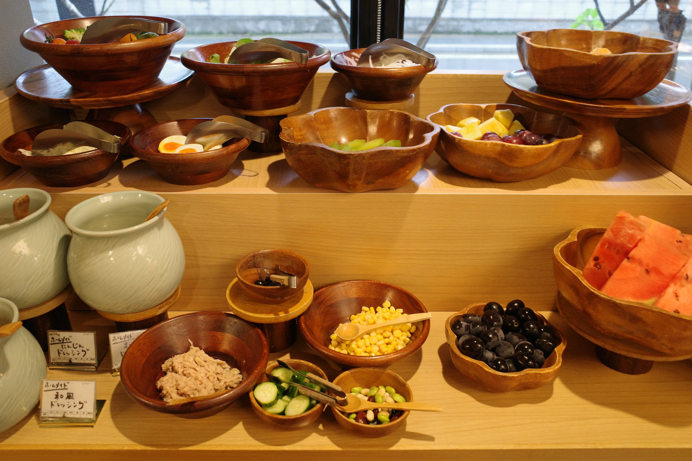 Wooden bowls of side dishes and a platter of watermelon by the window.