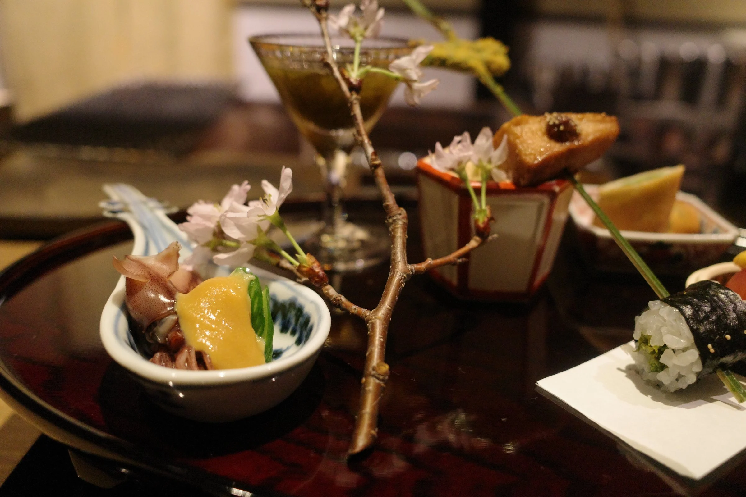 The hassun up close: a skewer, a cherry-blossom branch and small cups.