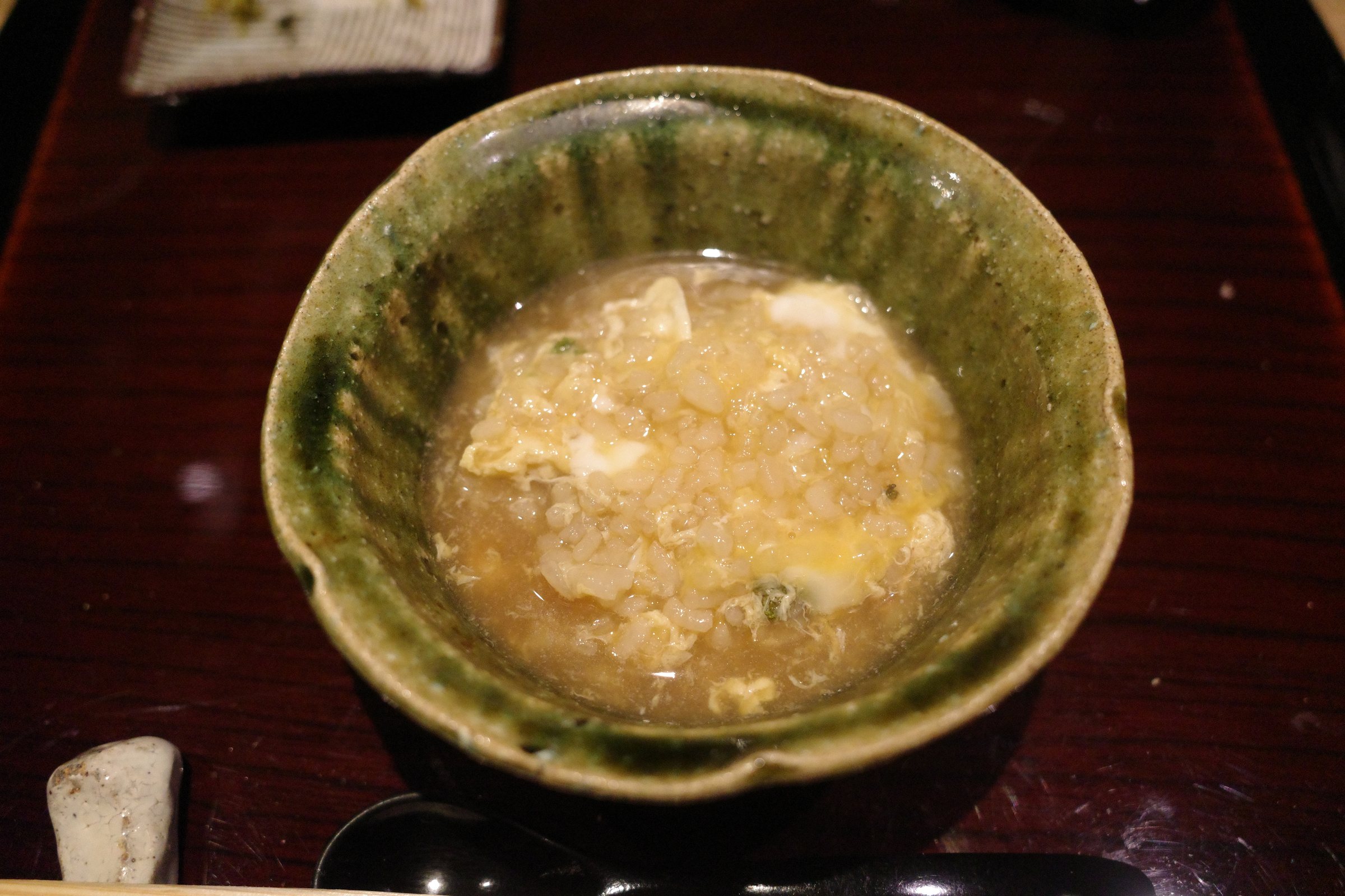 Rice porridge with egg in a green-glazed bowl.