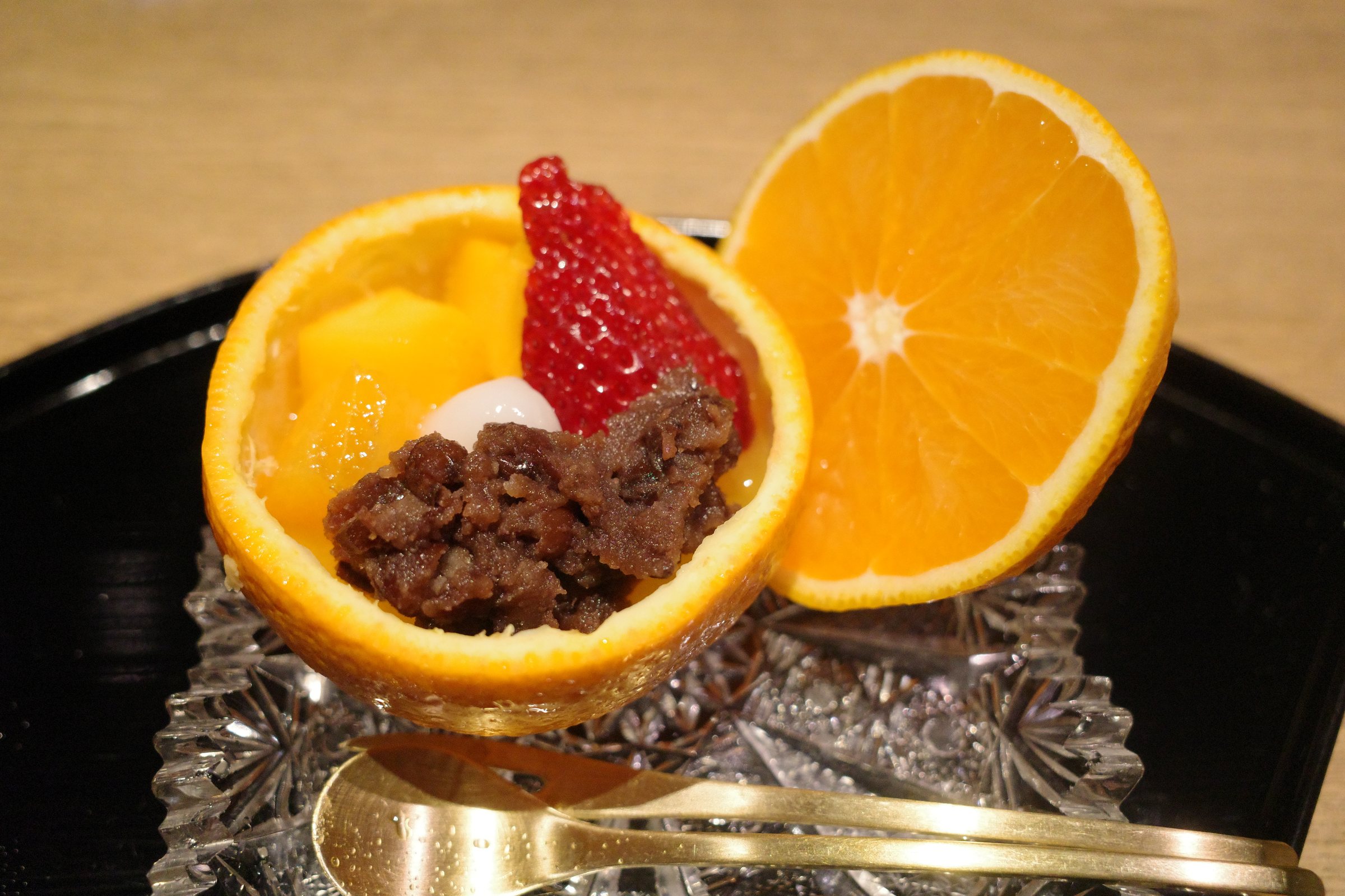 House-made sweet bean paste, a rice dumpling and strawberry in a hollowed orange, on a cut-glass dish.