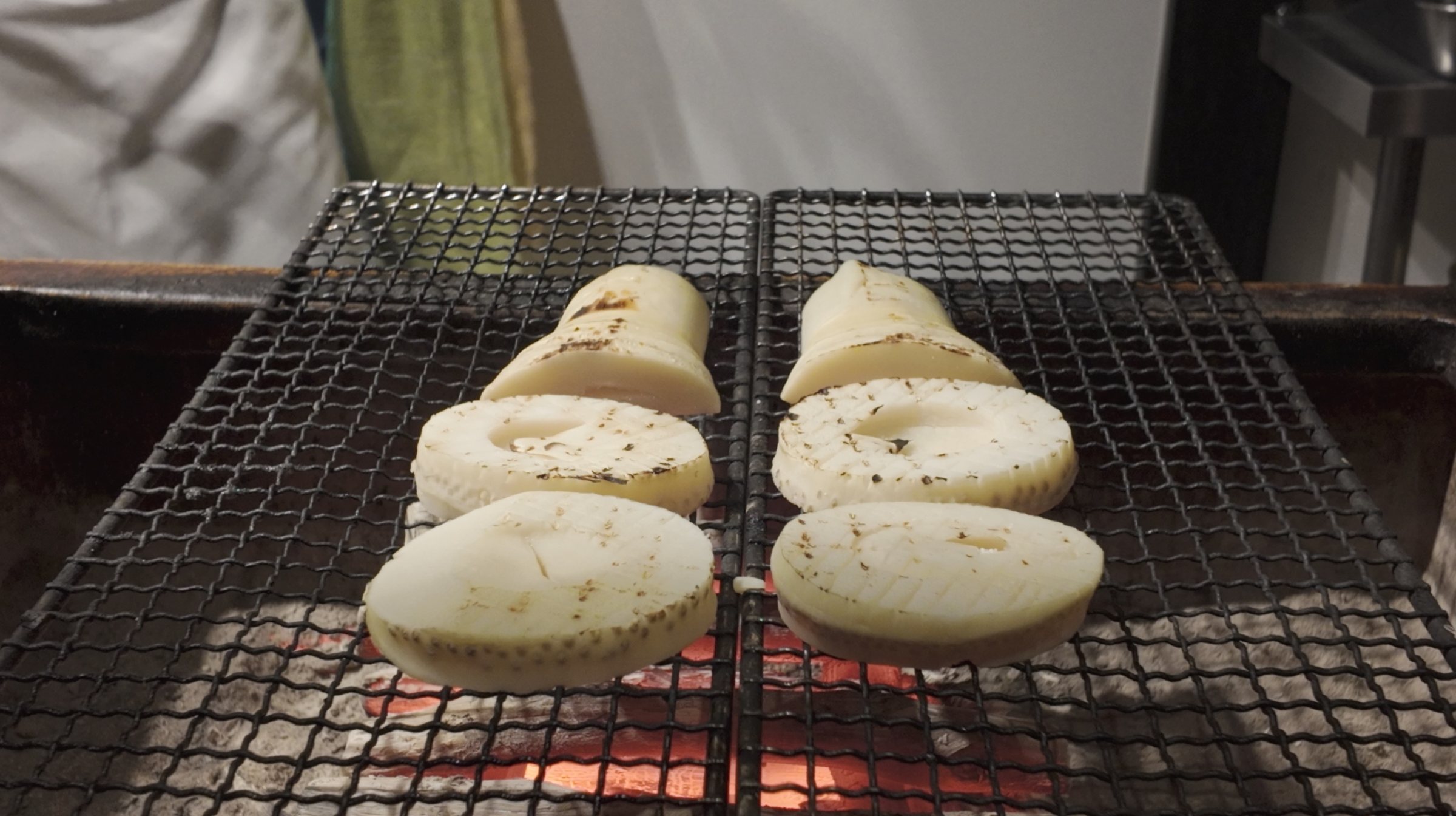 Bamboo shoots grilling over charcoal.