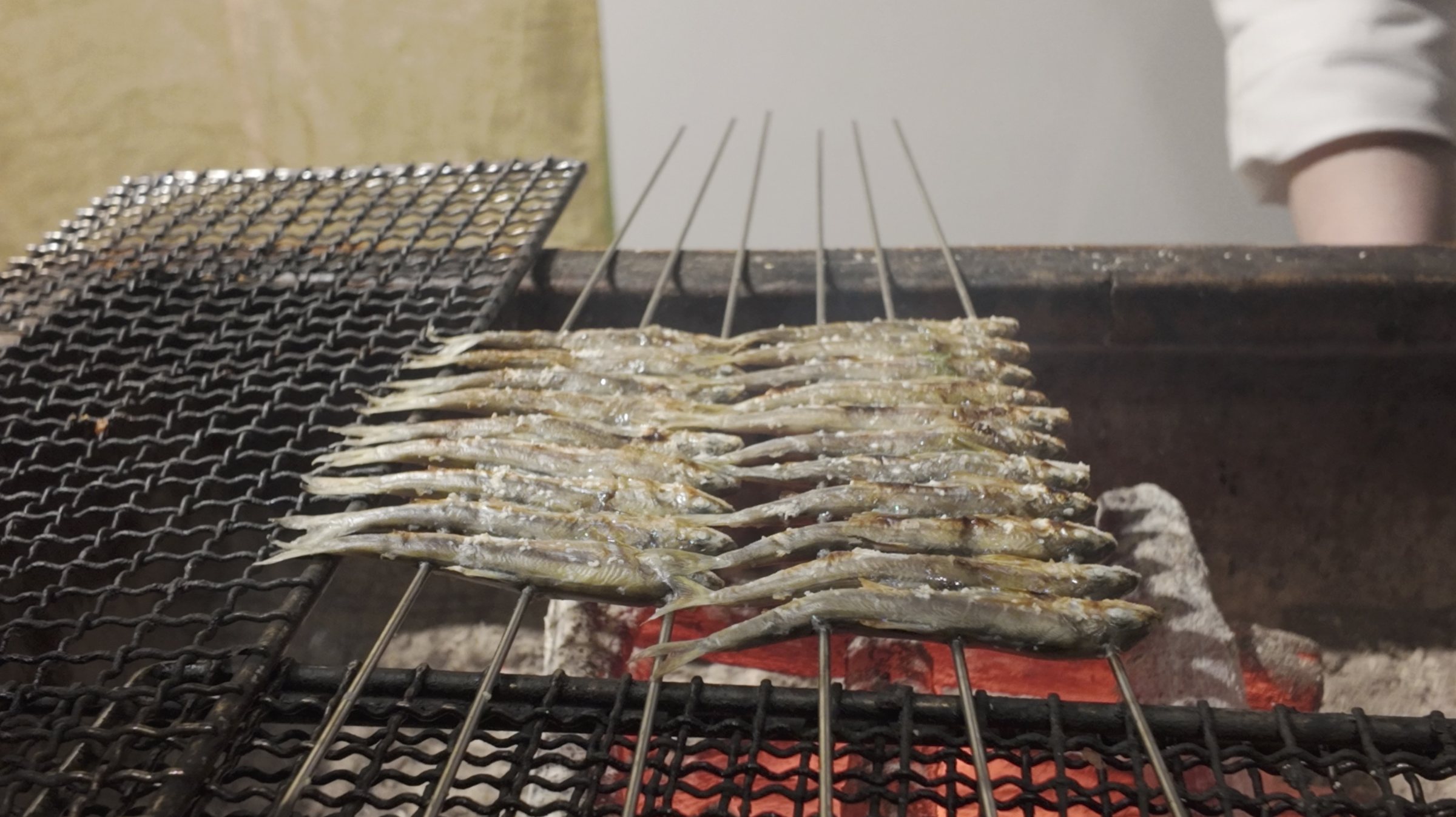 Small fish on skewers over the charcoal.