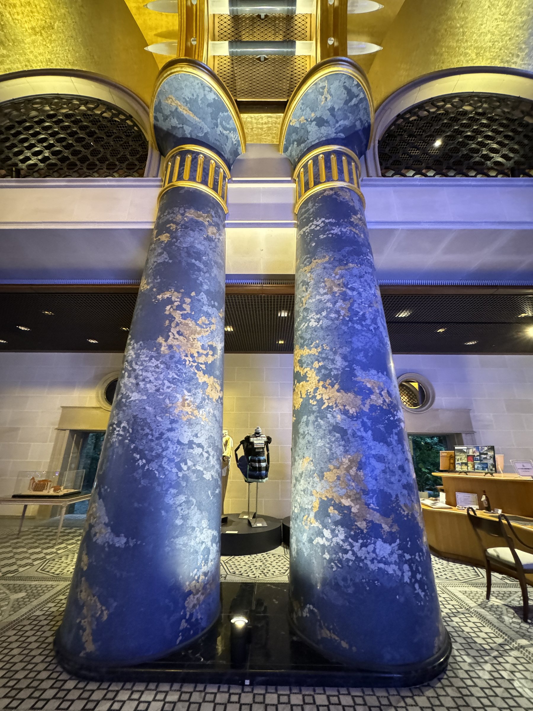 A pair of blue columns flecked with gold, rising from the mosaic floor.