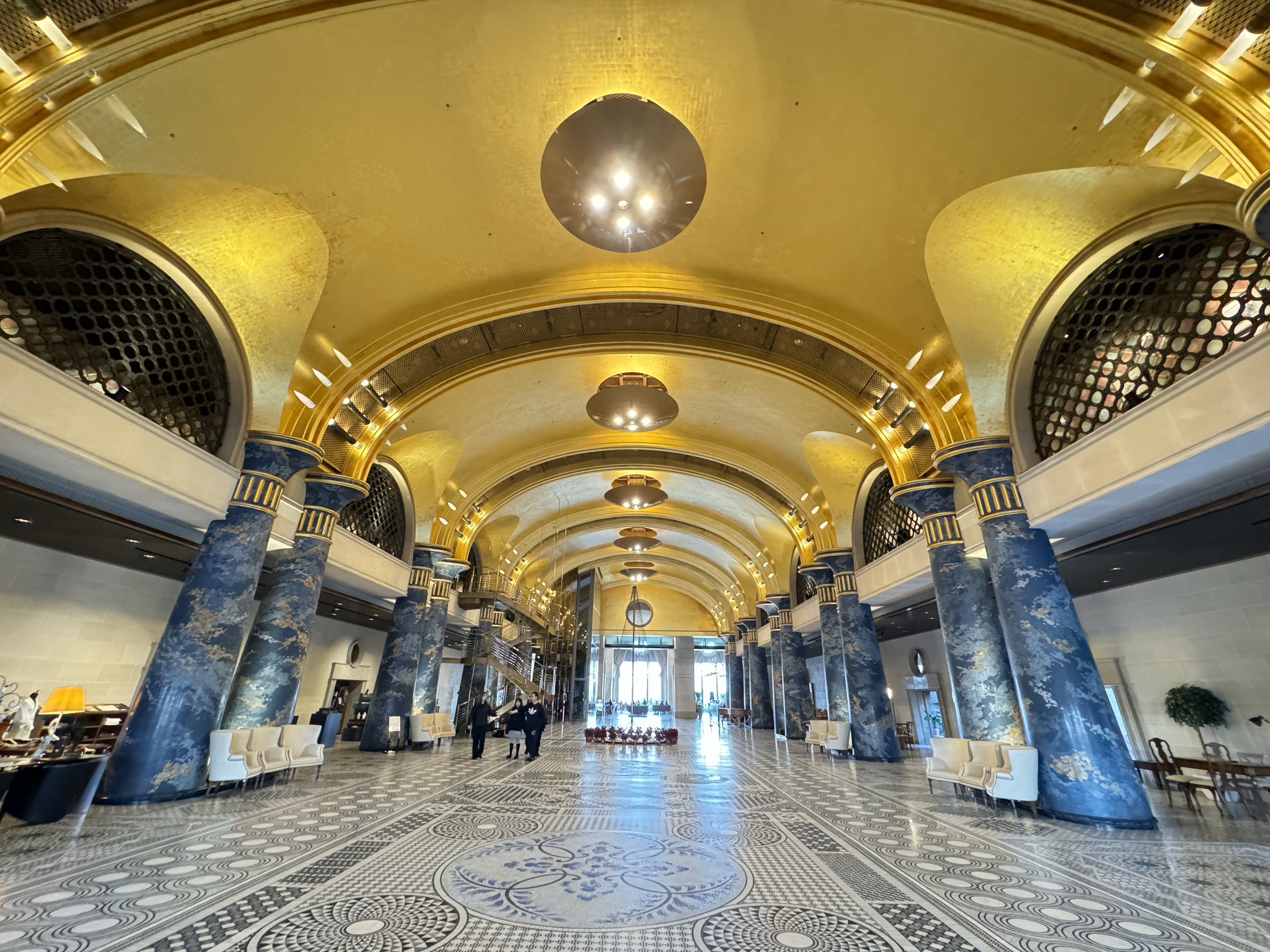 The gallery by day, lined with blue-and-gold columns over a mosaic floor.