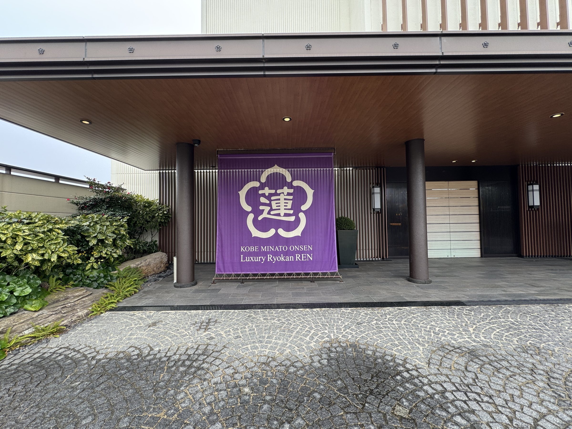 The entrance, hung with a purple banner reading “Kobe Minato Onsen Luxury Ryokan REN”.