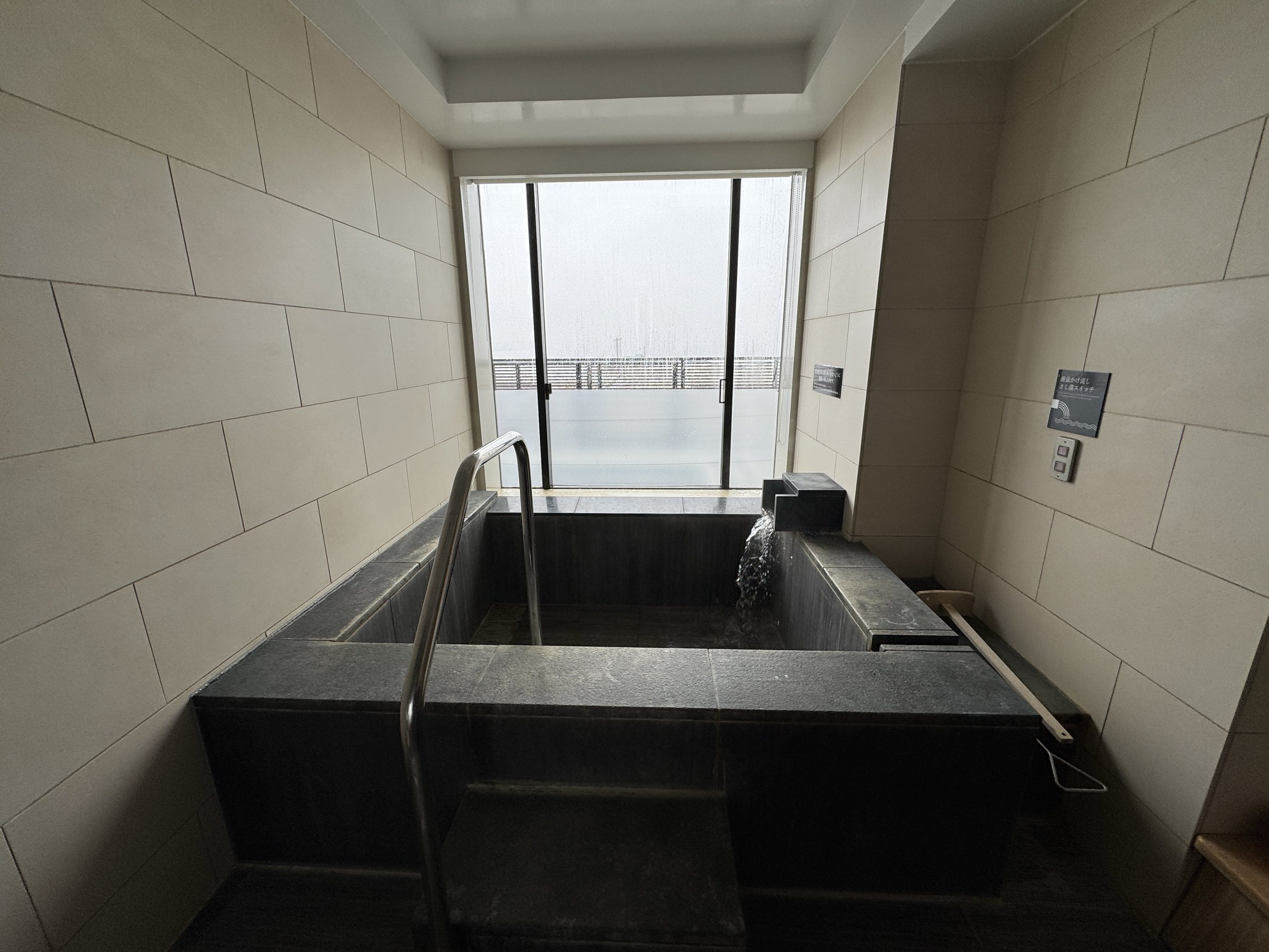 The in-room hot-spring bath, with the sea beyond the glass.