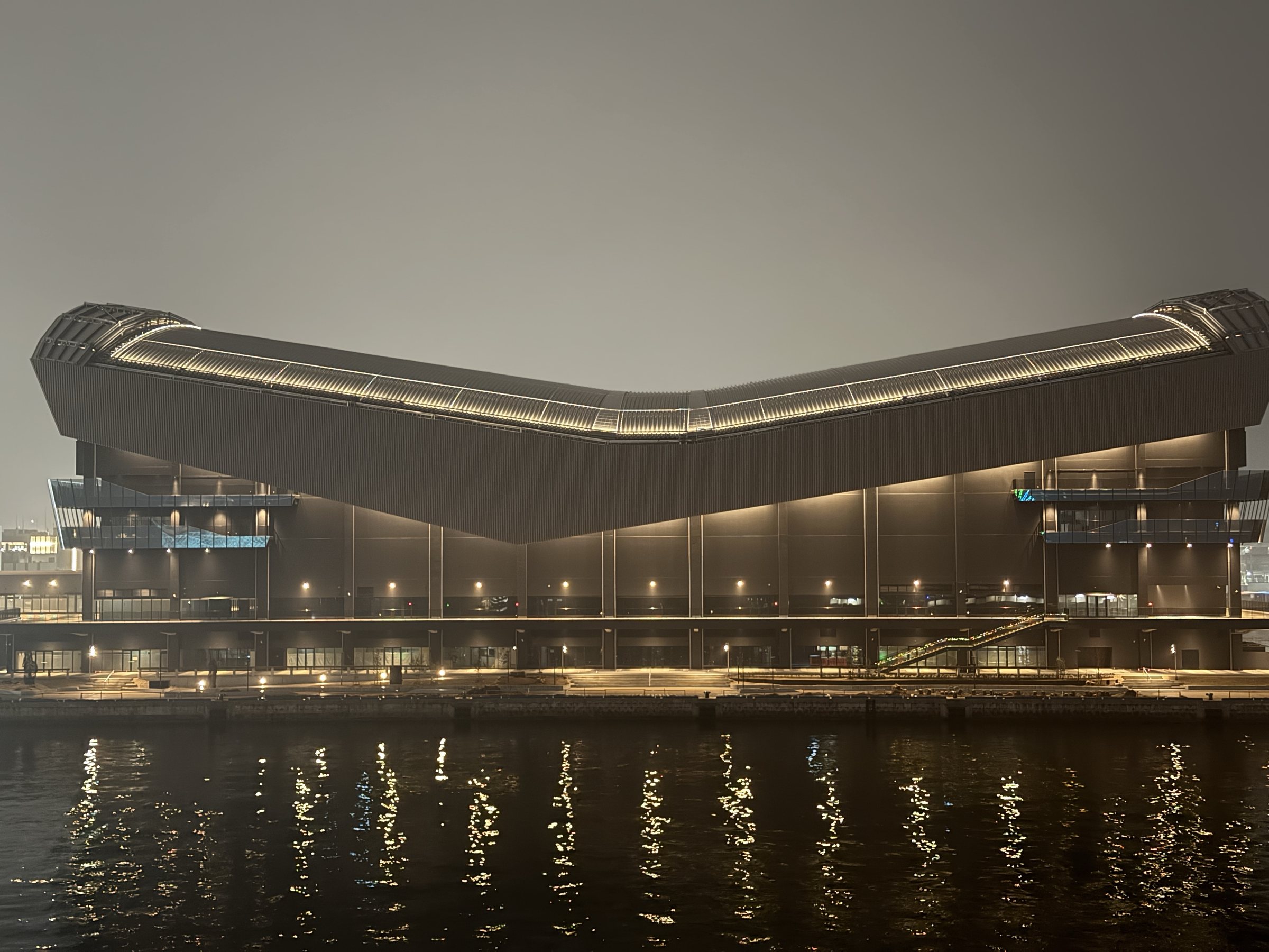The arena lit up across the water at night.