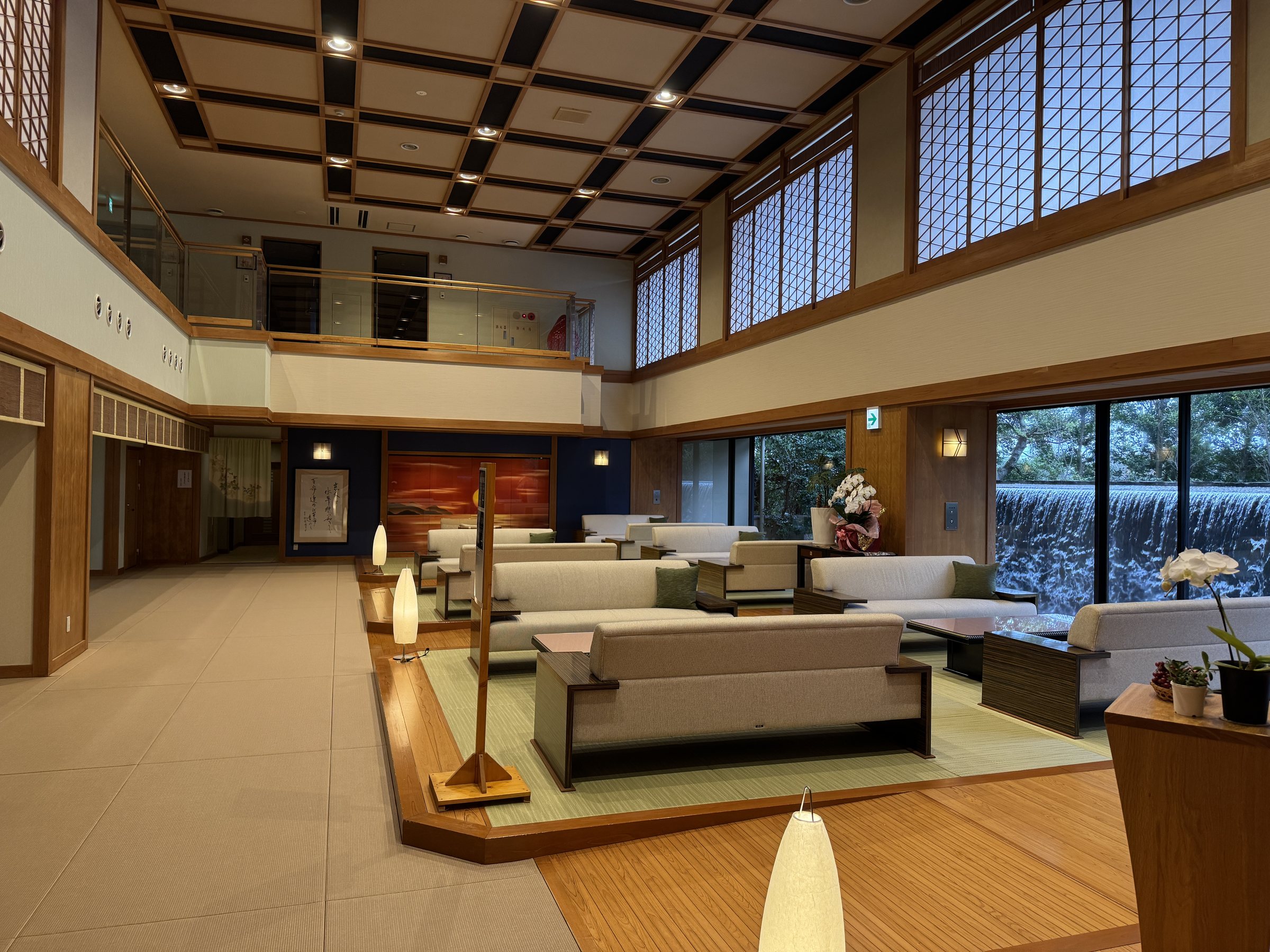 The large lounge: sofas, a red sunset painting and tall windows onto the garden.
