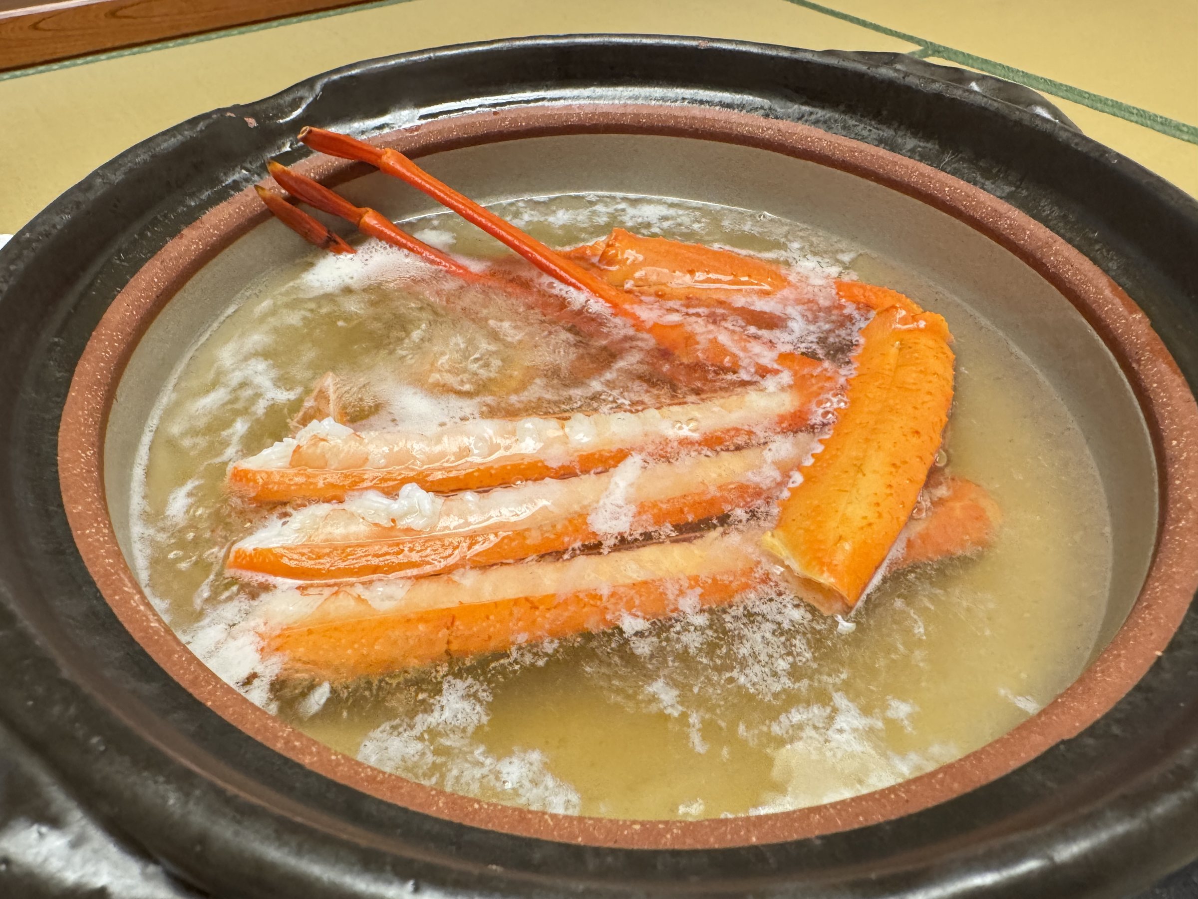 Crab legs simmering in an earthenware hotpot.