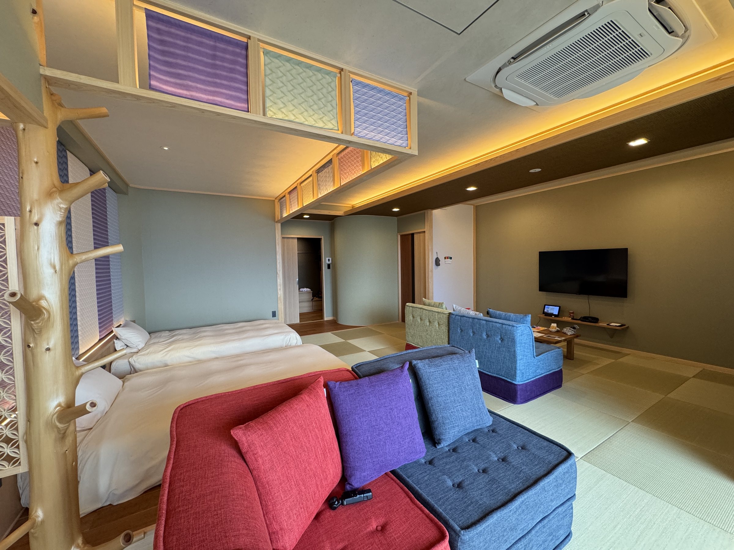 The living area: a red sofa, purple and blue armchairs and tatami beyond.