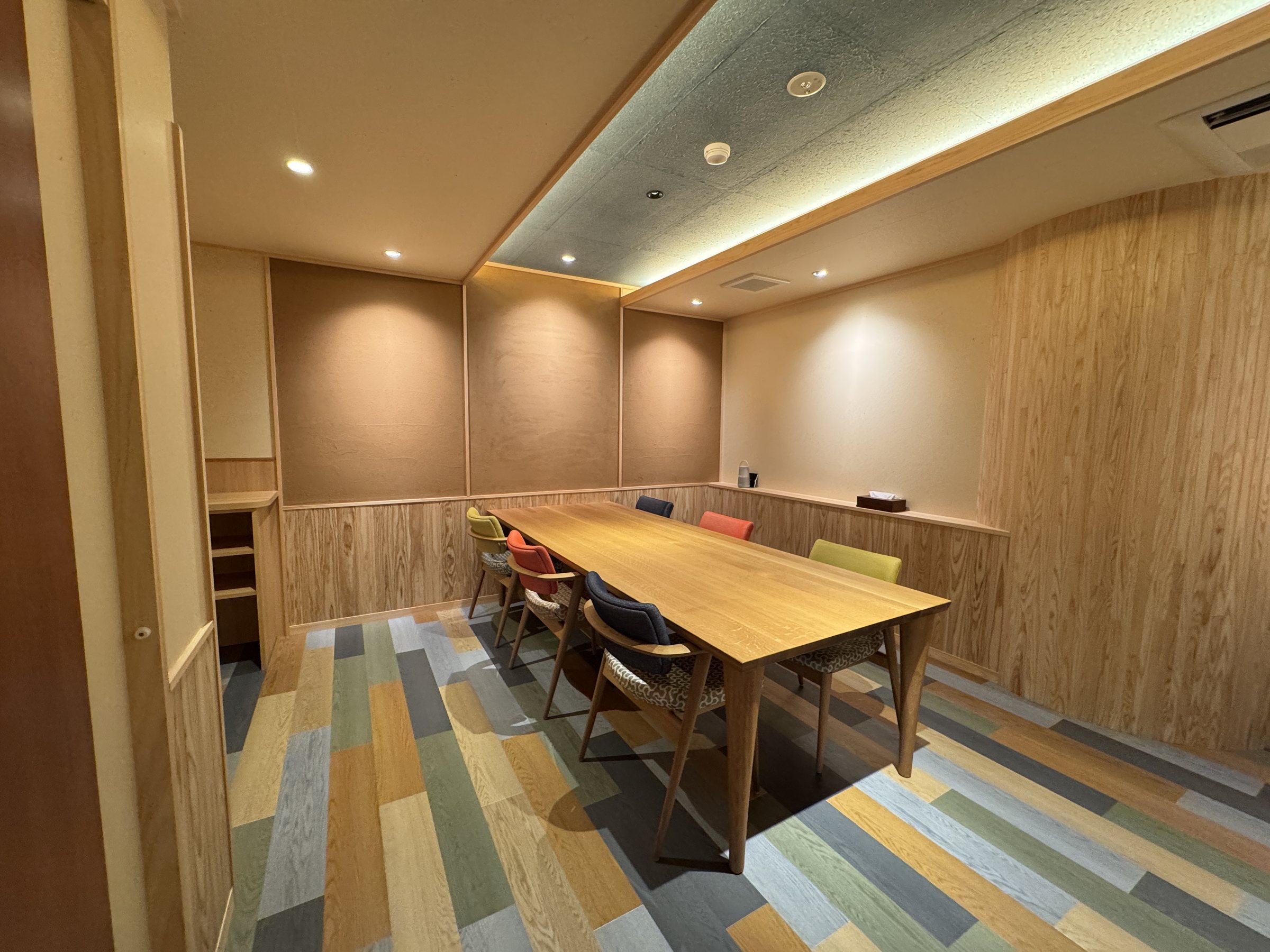 The dining area, with a long table and colorful chairs.