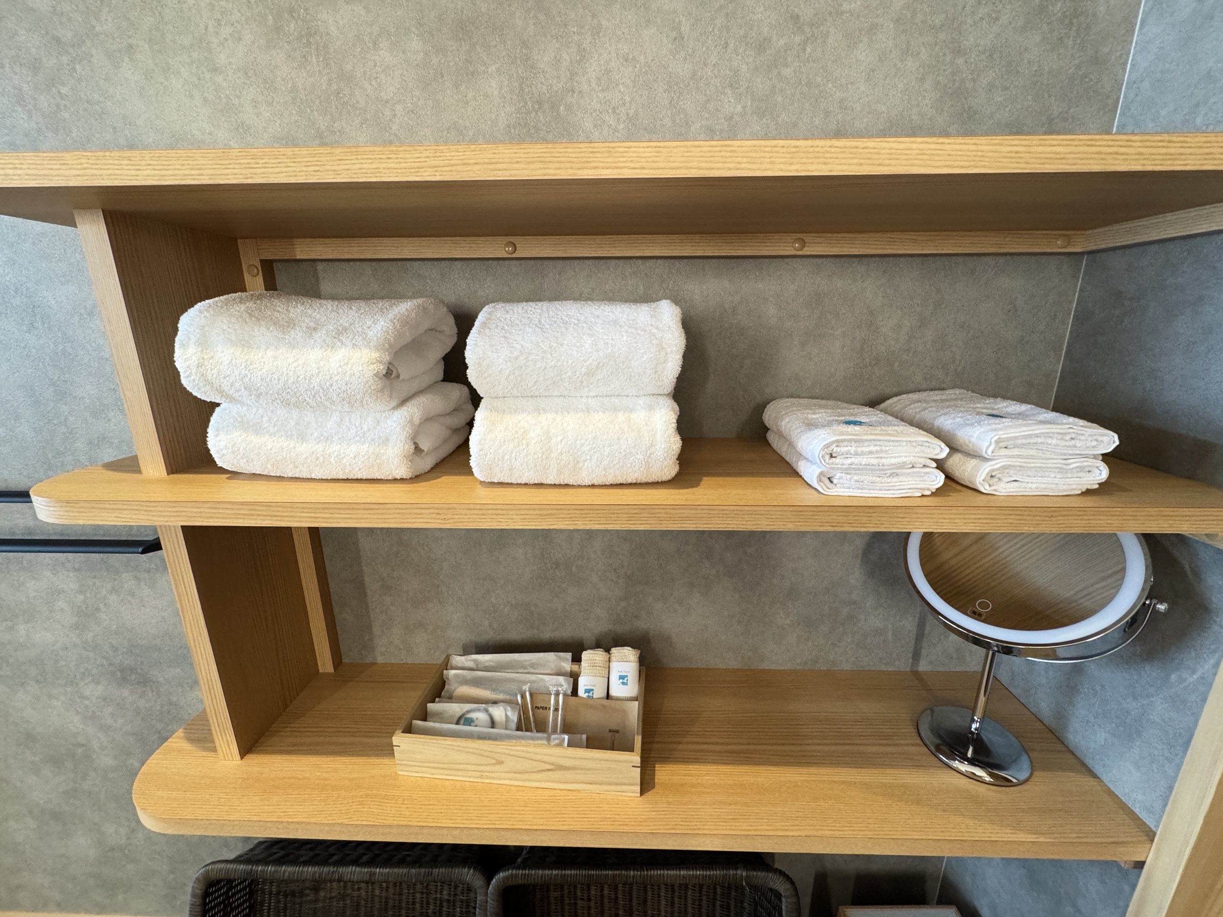 Towels on open shelves, with a freestanding make-up mirror.