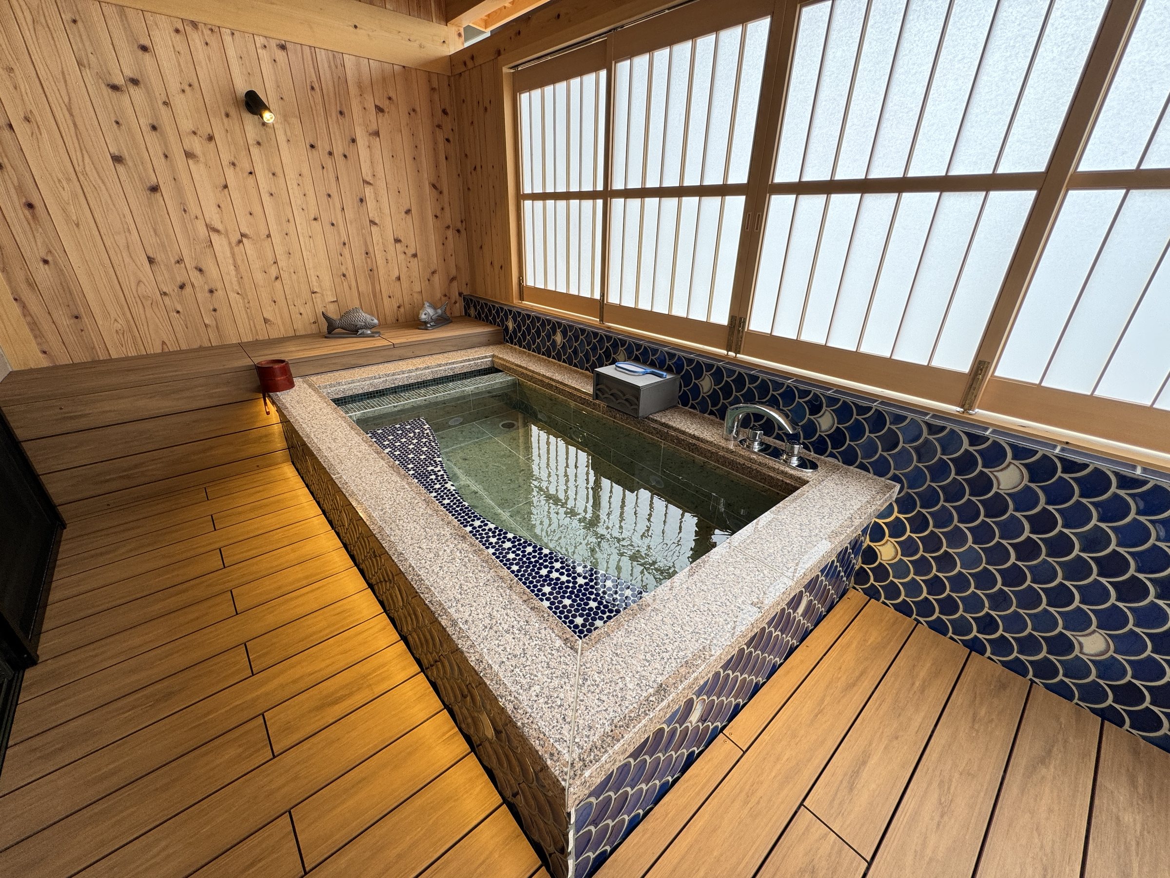 The in-room bath, lined with patterned tiles, under a cedar ceiling.