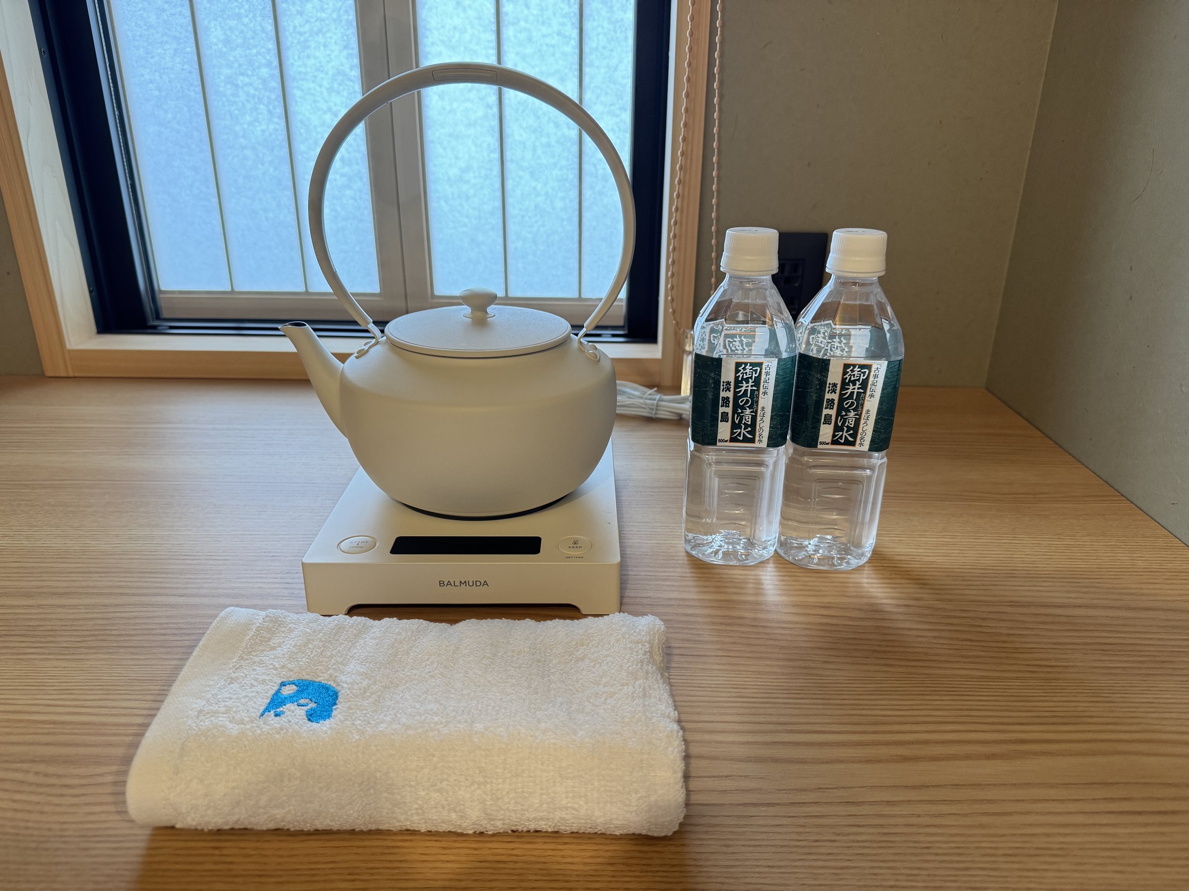 A white kettle, bottled water and a folded towel.