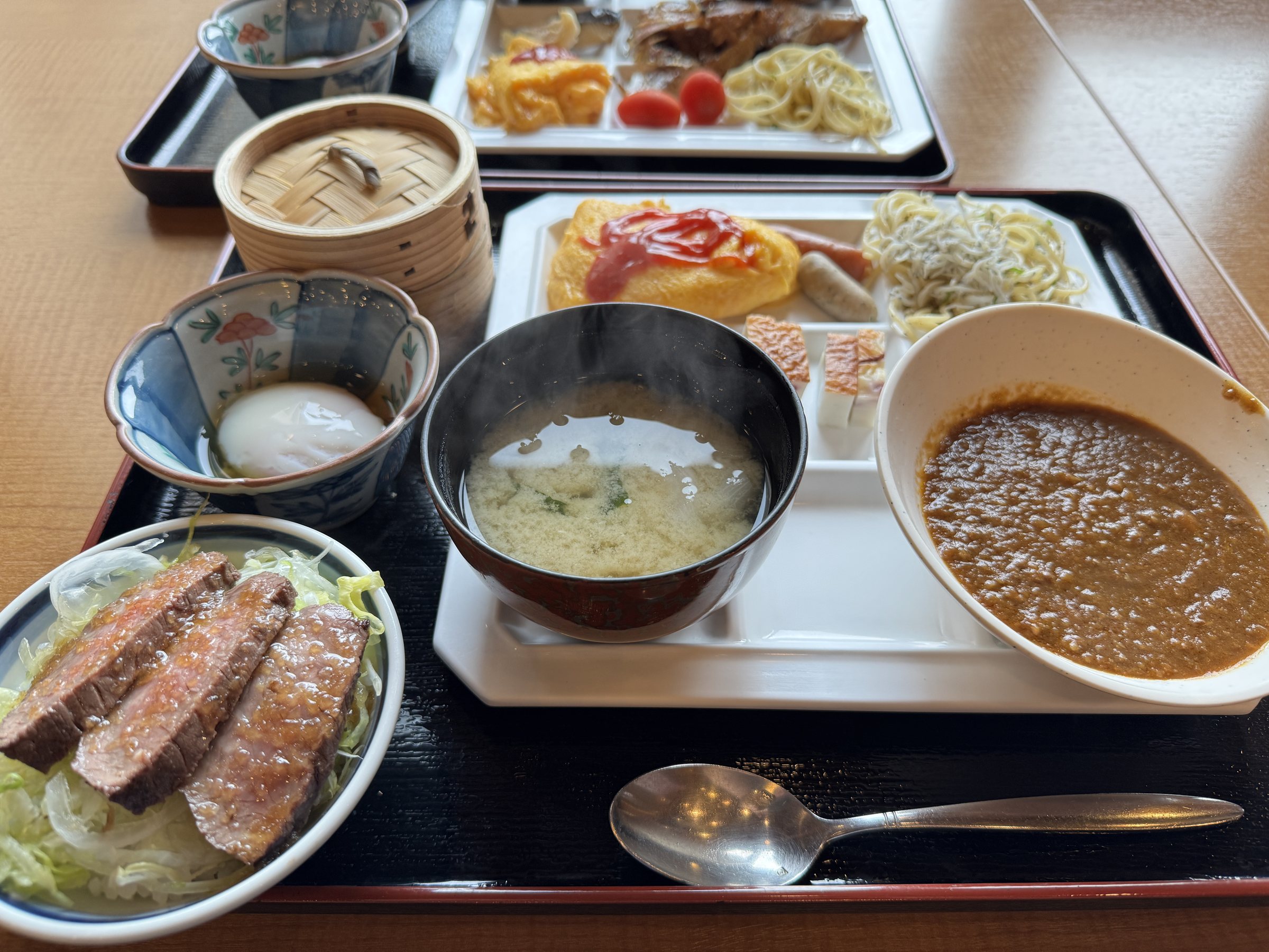 A plate from the buffet: steak, curry, soup and small dishes.
