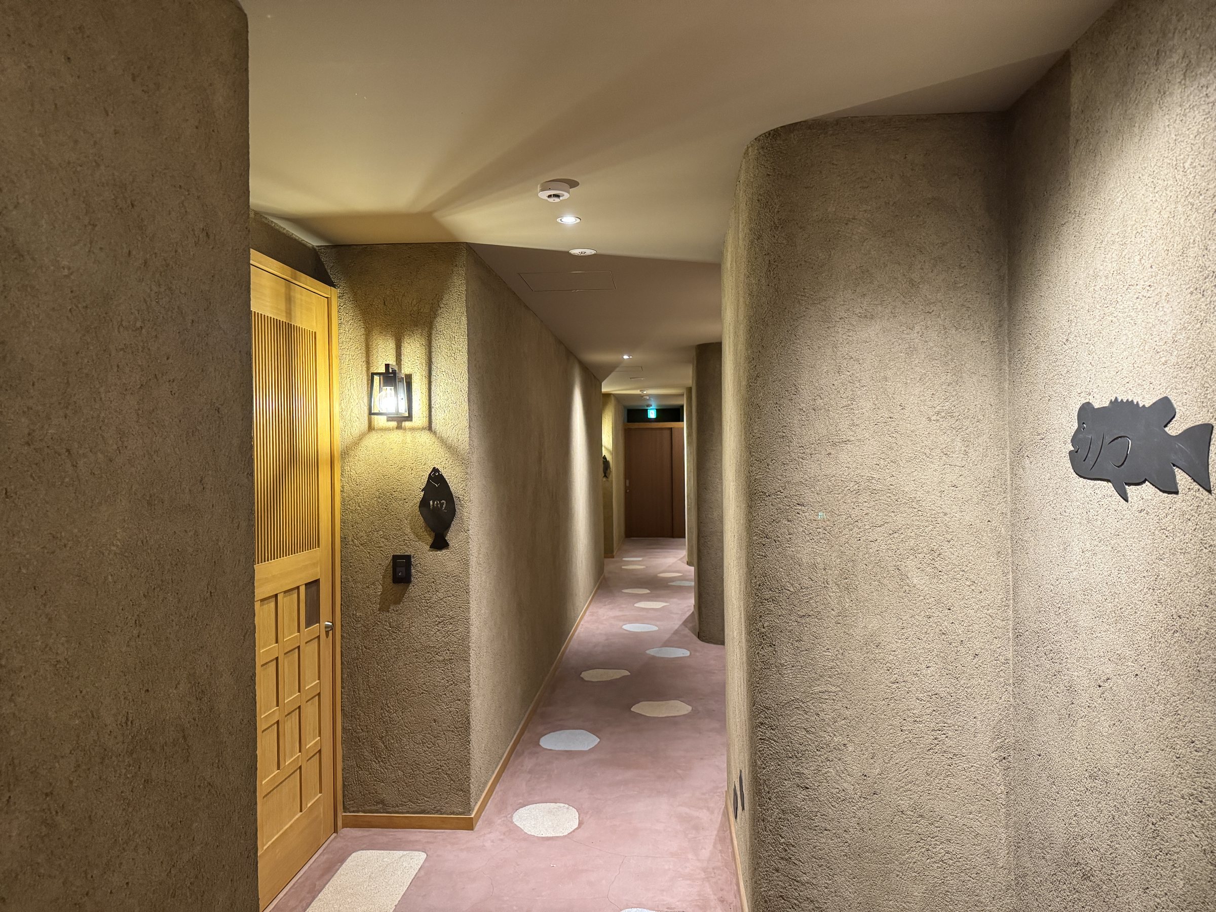 A corridor wall with a fish motif and pebble-like spots on the carpet.