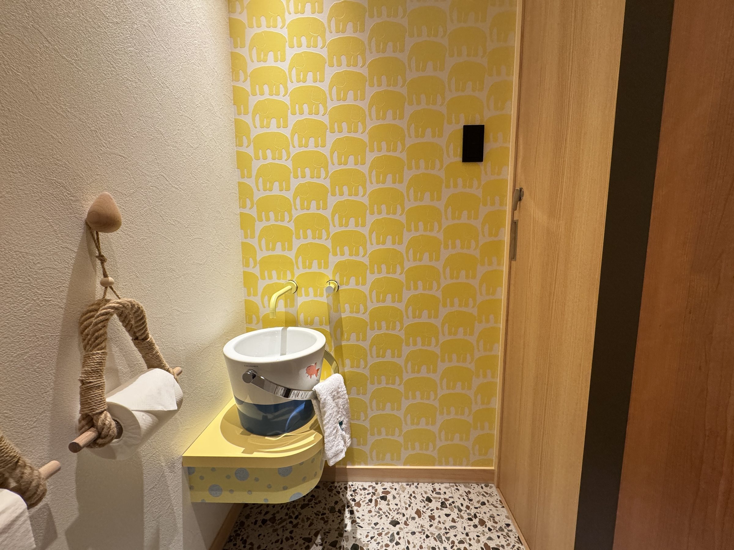 A playful toilet with a yellow patterned wall.