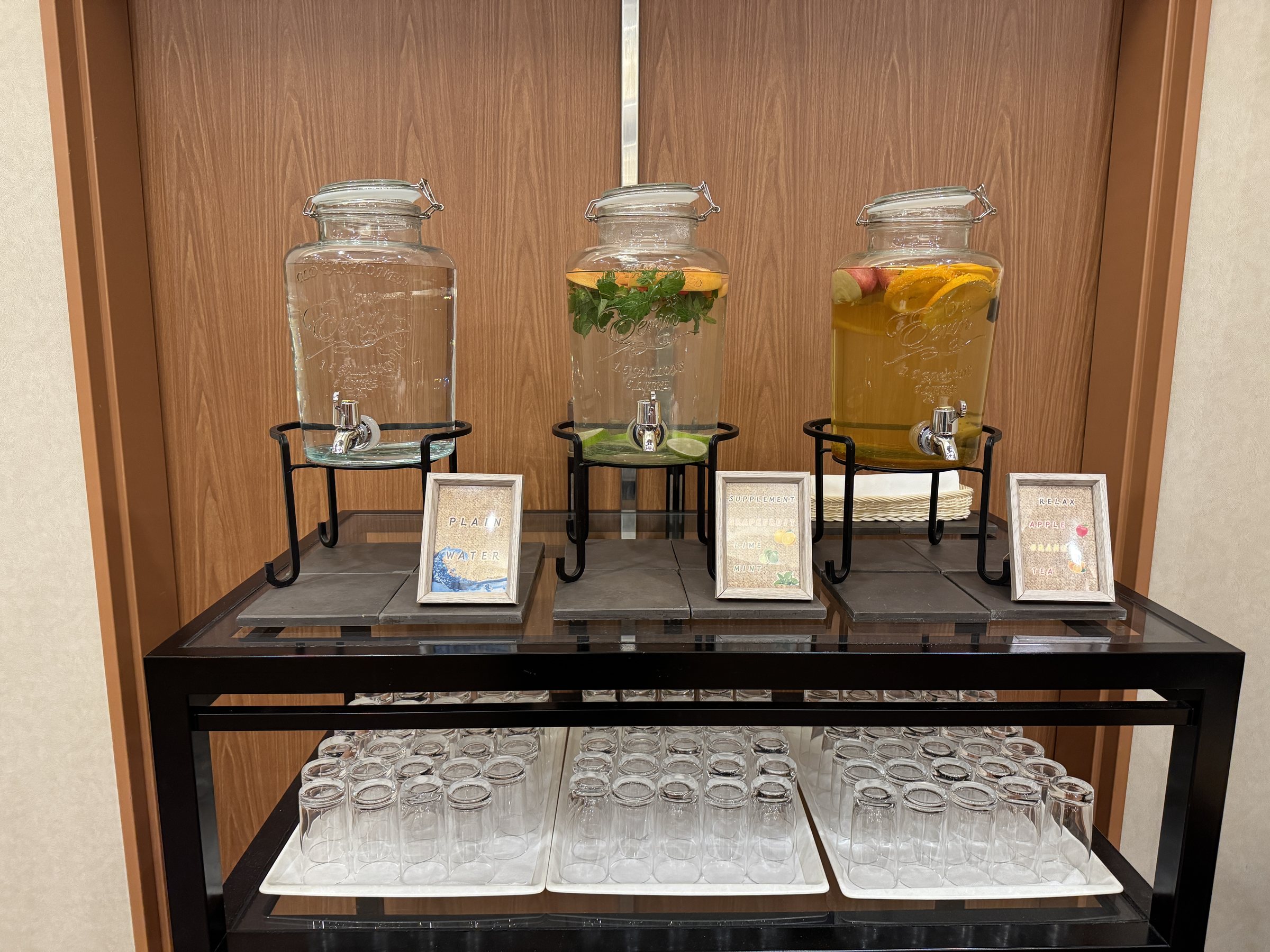 Infused water with fruit and herbs in glass dispensers.