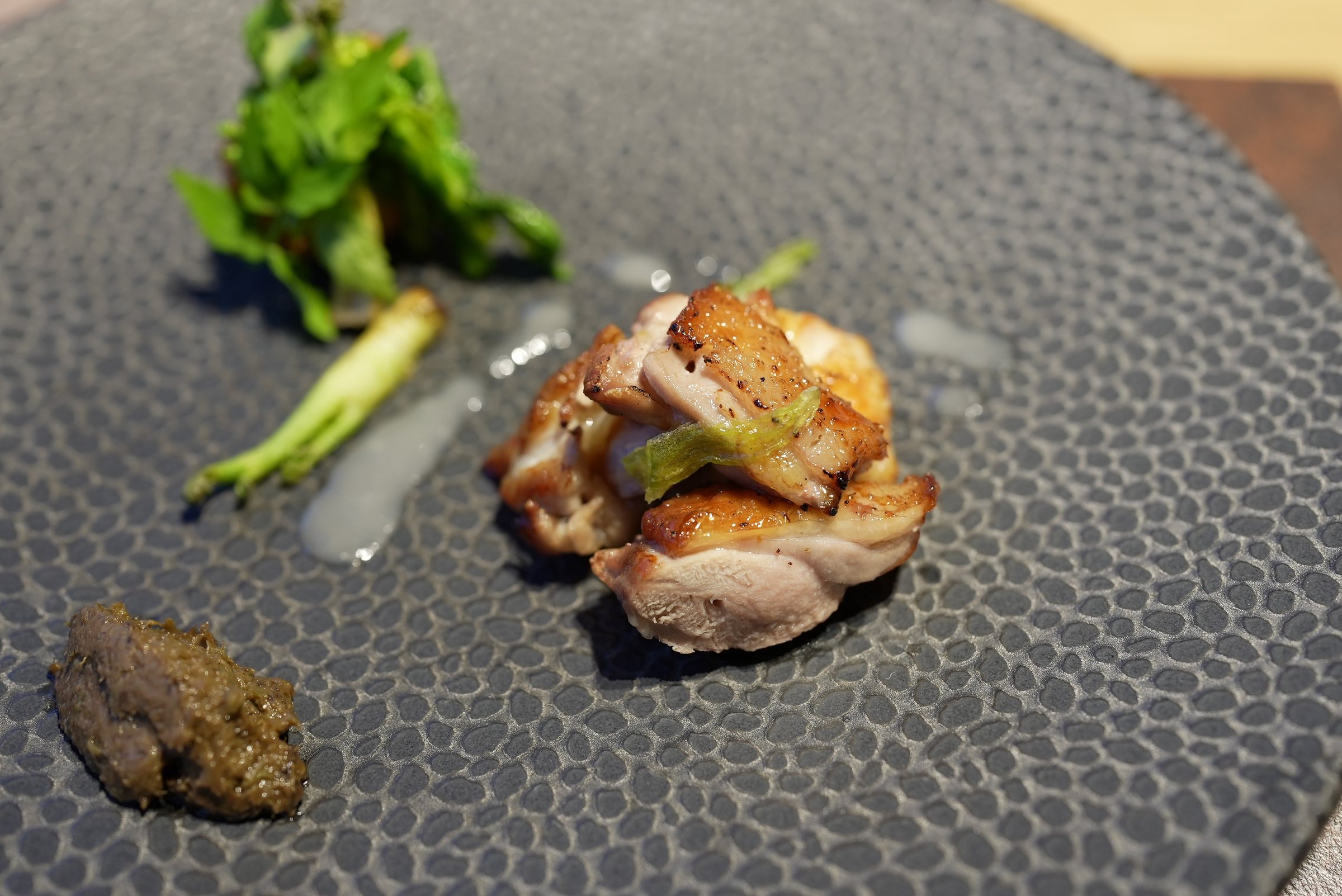 Charcoal-grilled shamo chicken, with greens and a dark paste of butterbur shoots.