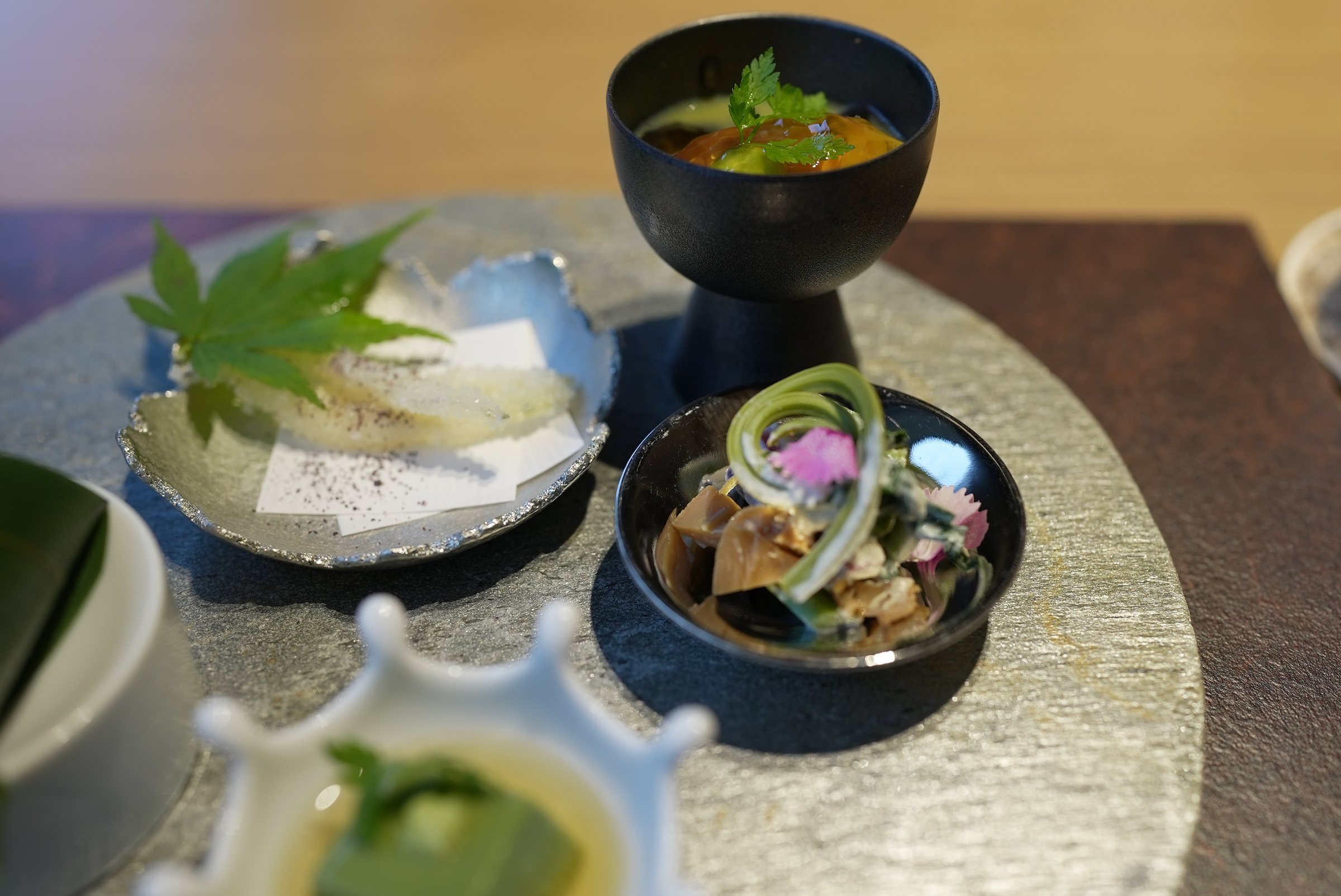 Detail: small bowls of spring vegetables, jellies and dressed greens.