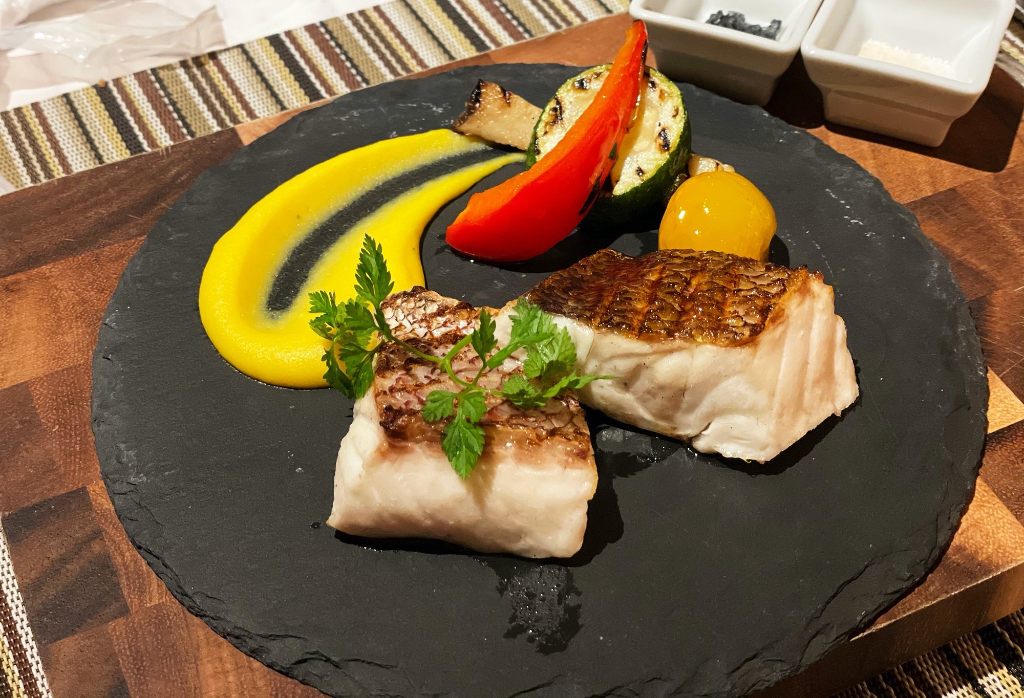 Pan-crisped tilefish on slate, with a bright yellow purée and grilled vegetables.