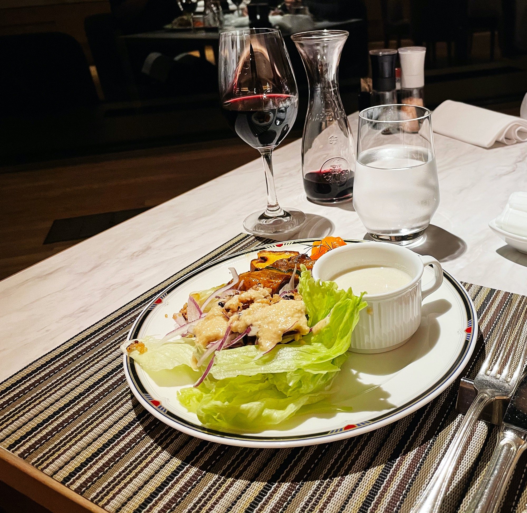 From the buffet: a plate of salad and a creamy soup, with a glass of red.
