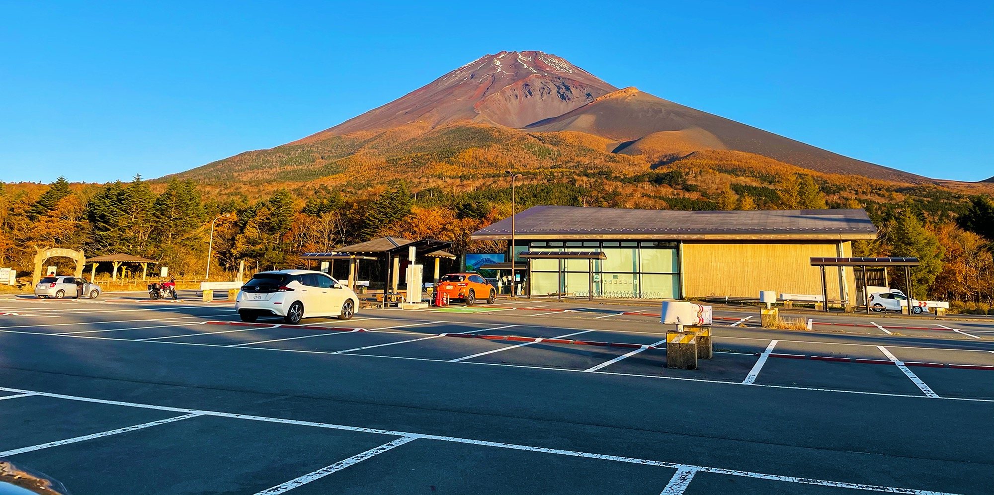 Fuji's full silhouette above the parking lot and autumn trees.