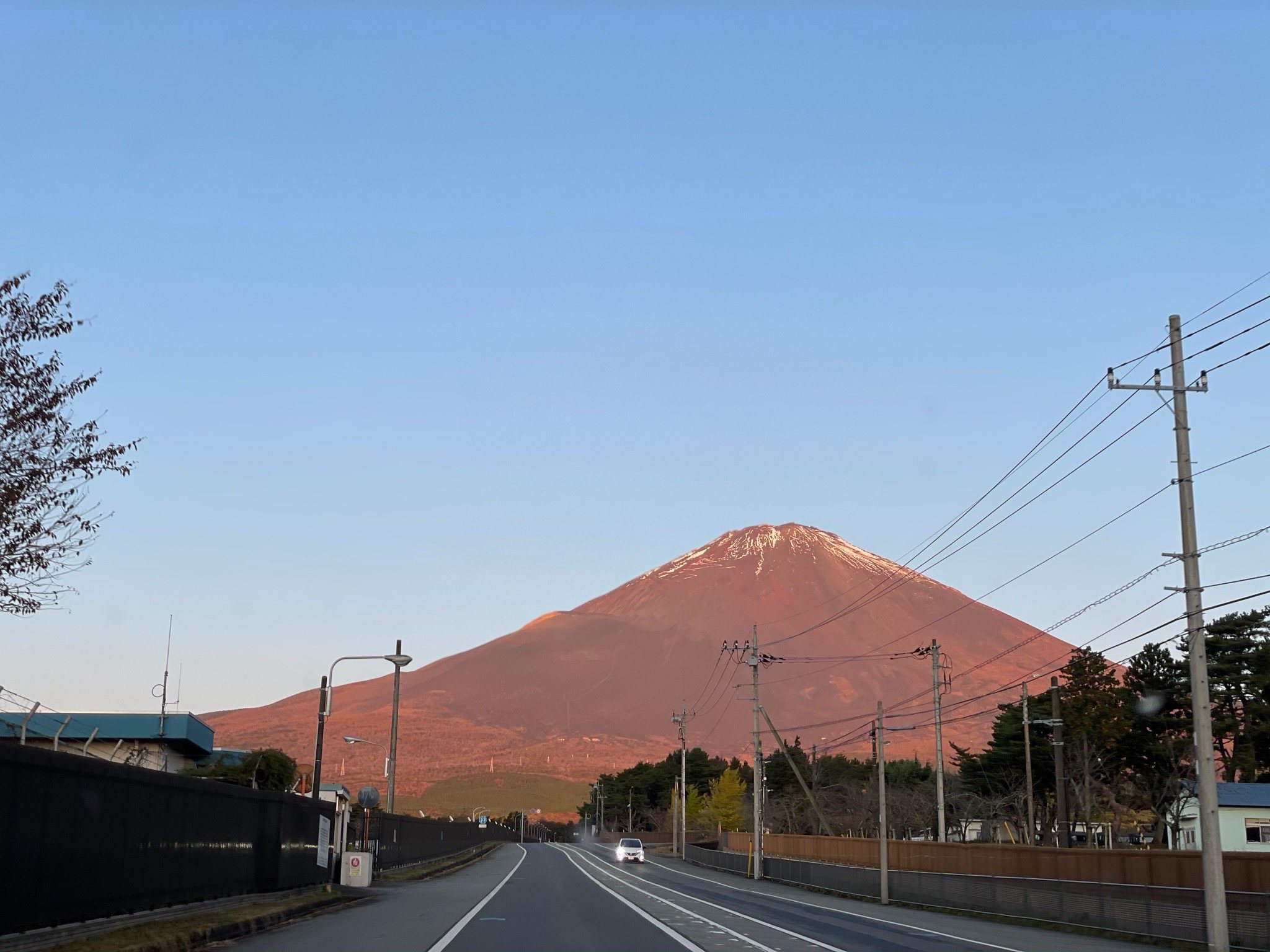 Dawn on the road to the mountain, Fuji flushed red at its end.
