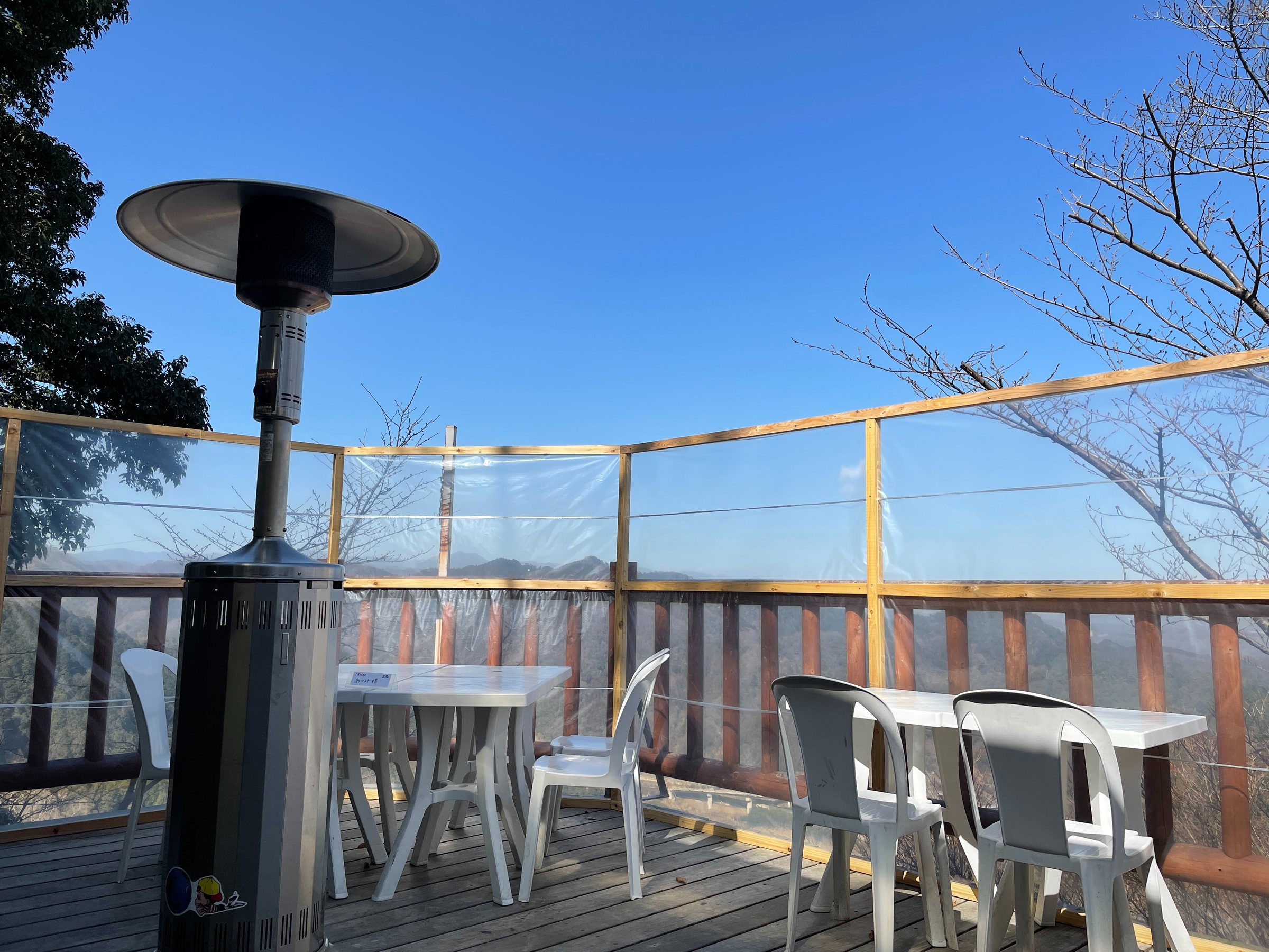 The open-air terrace: white tables, a patio heater and a sweep of blue sky.