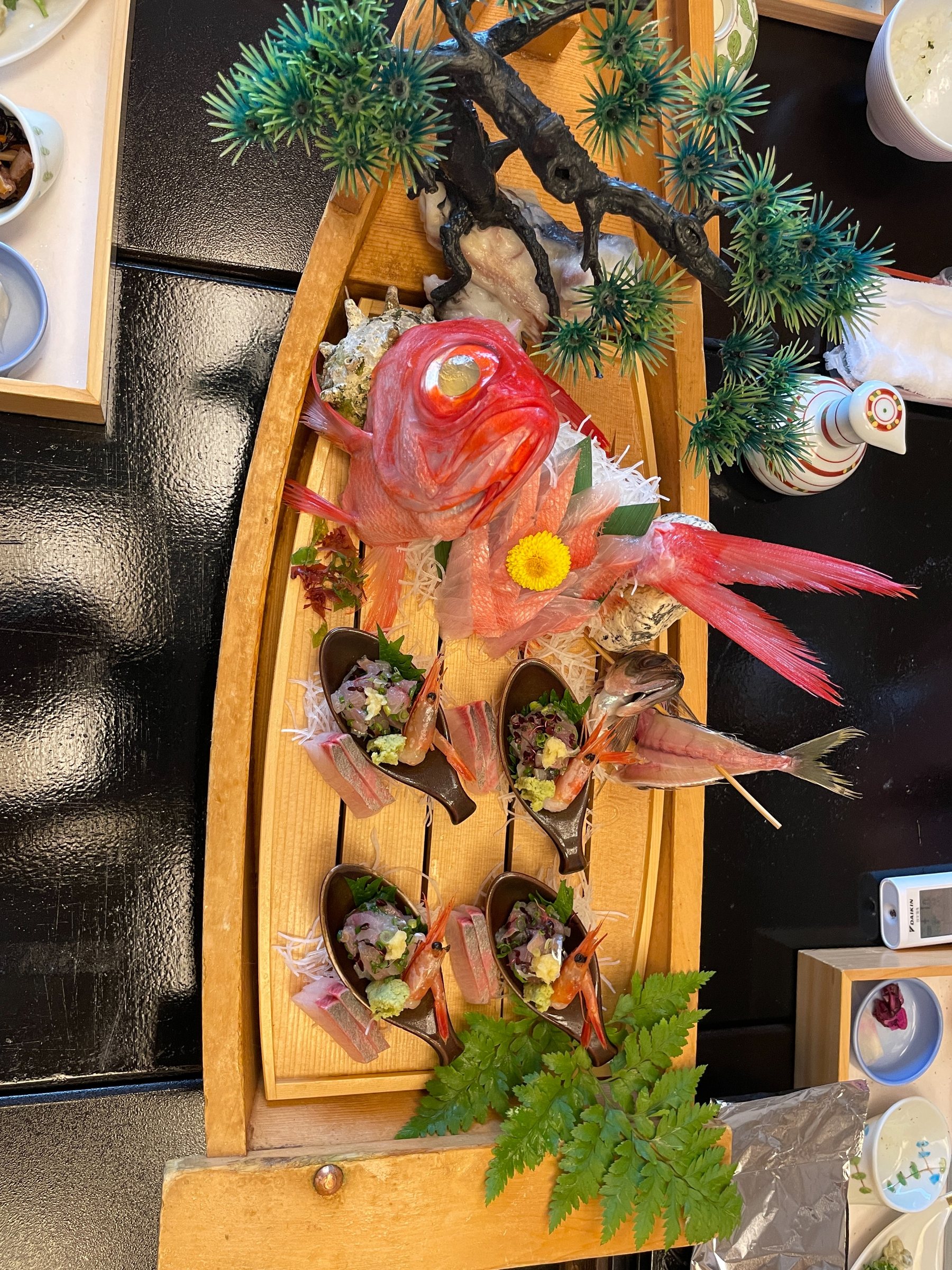 A breakfast sashimi boat, decorated with pine and a whole red fish.